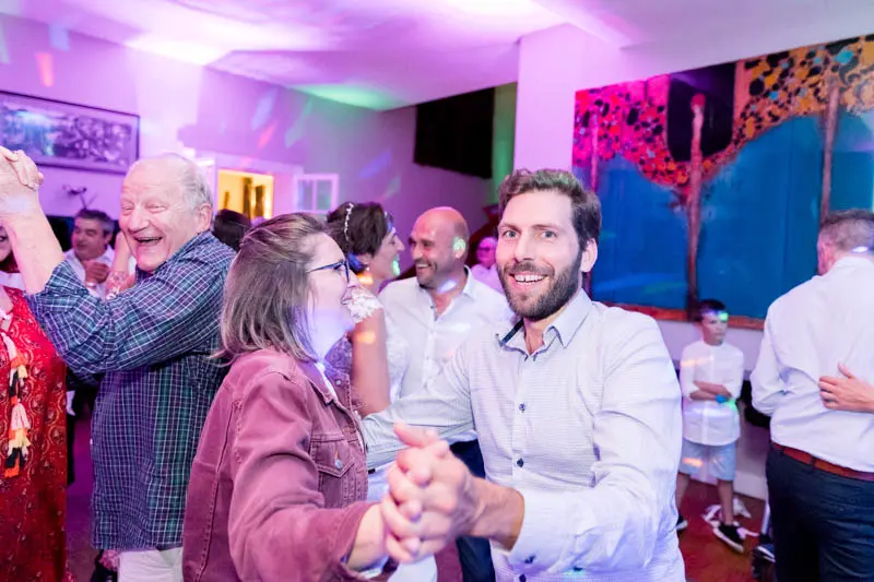 Guests dancing in pairs under the colourful lights of the wedding party