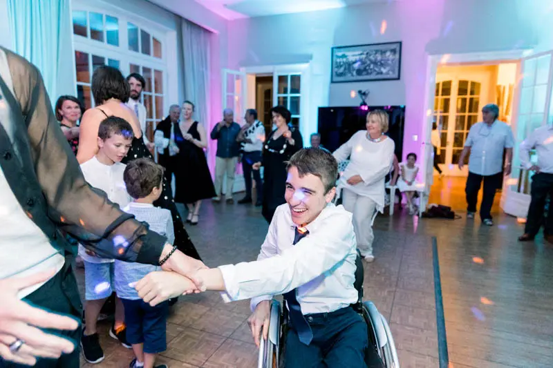 A young guest in a wheelchair dances with the other guests during the party