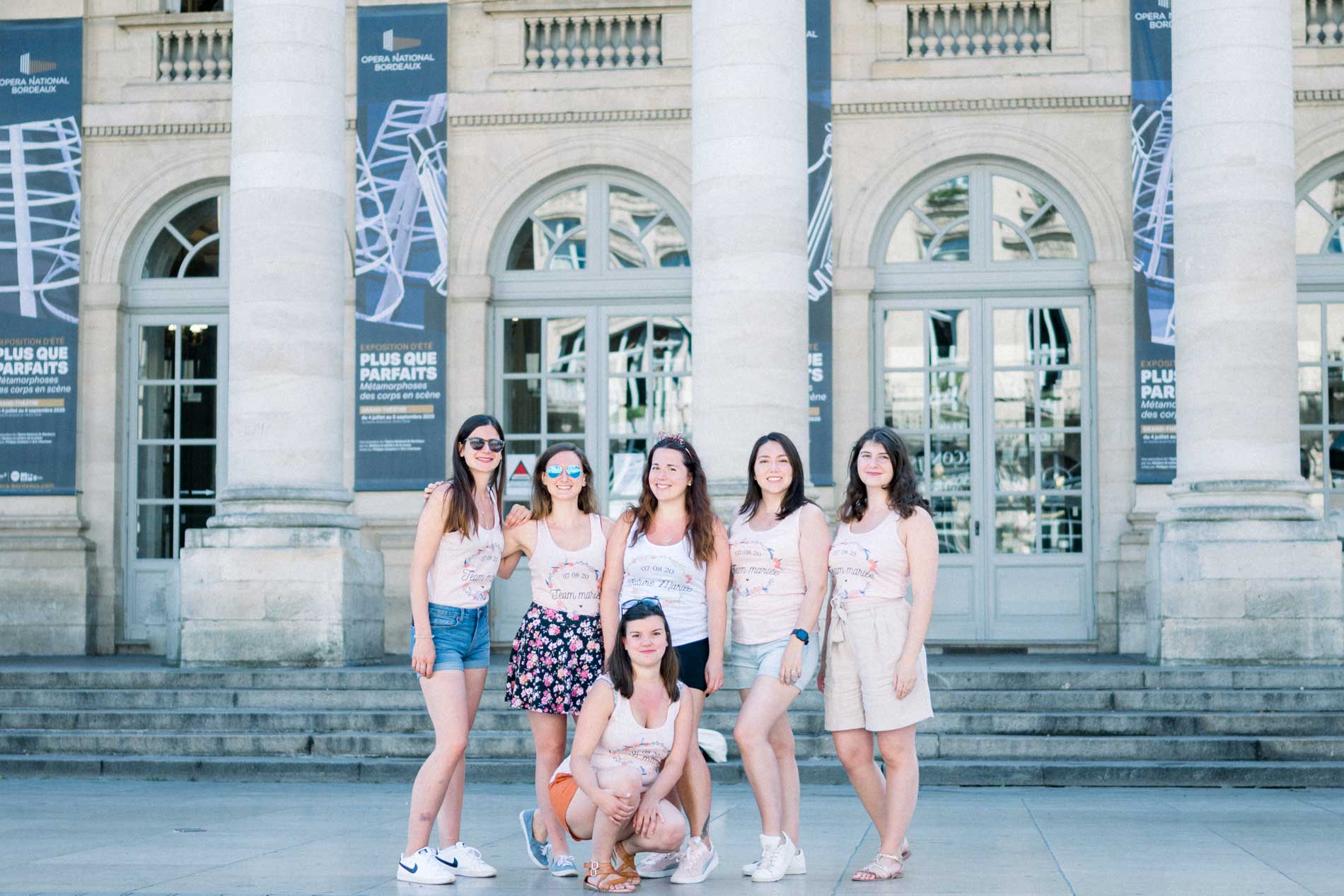 Hen party group posing before the columns of a classical theatre in Bordeaux