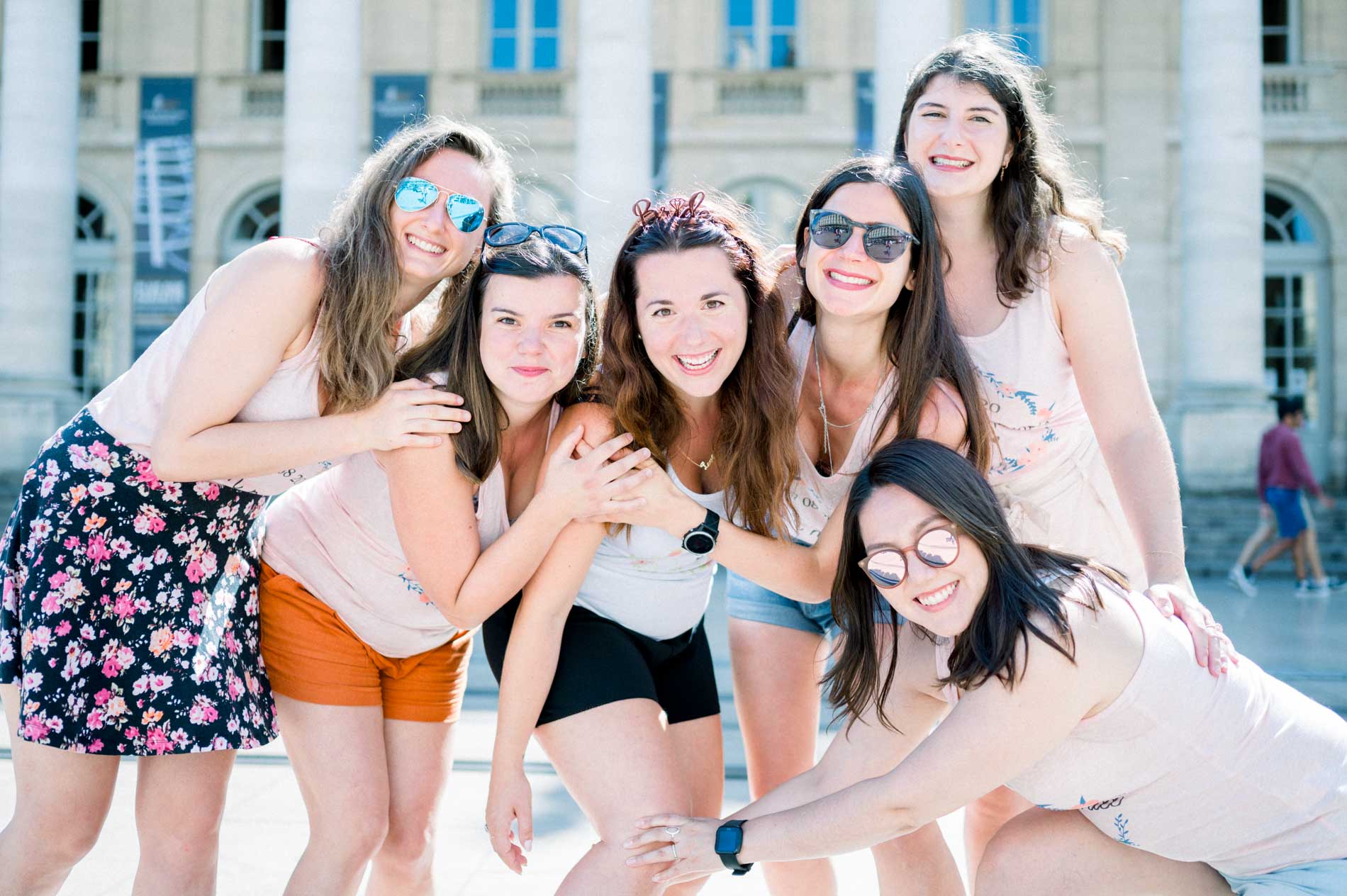 Friends in sunglasses squeezed together, laughing during the hen party