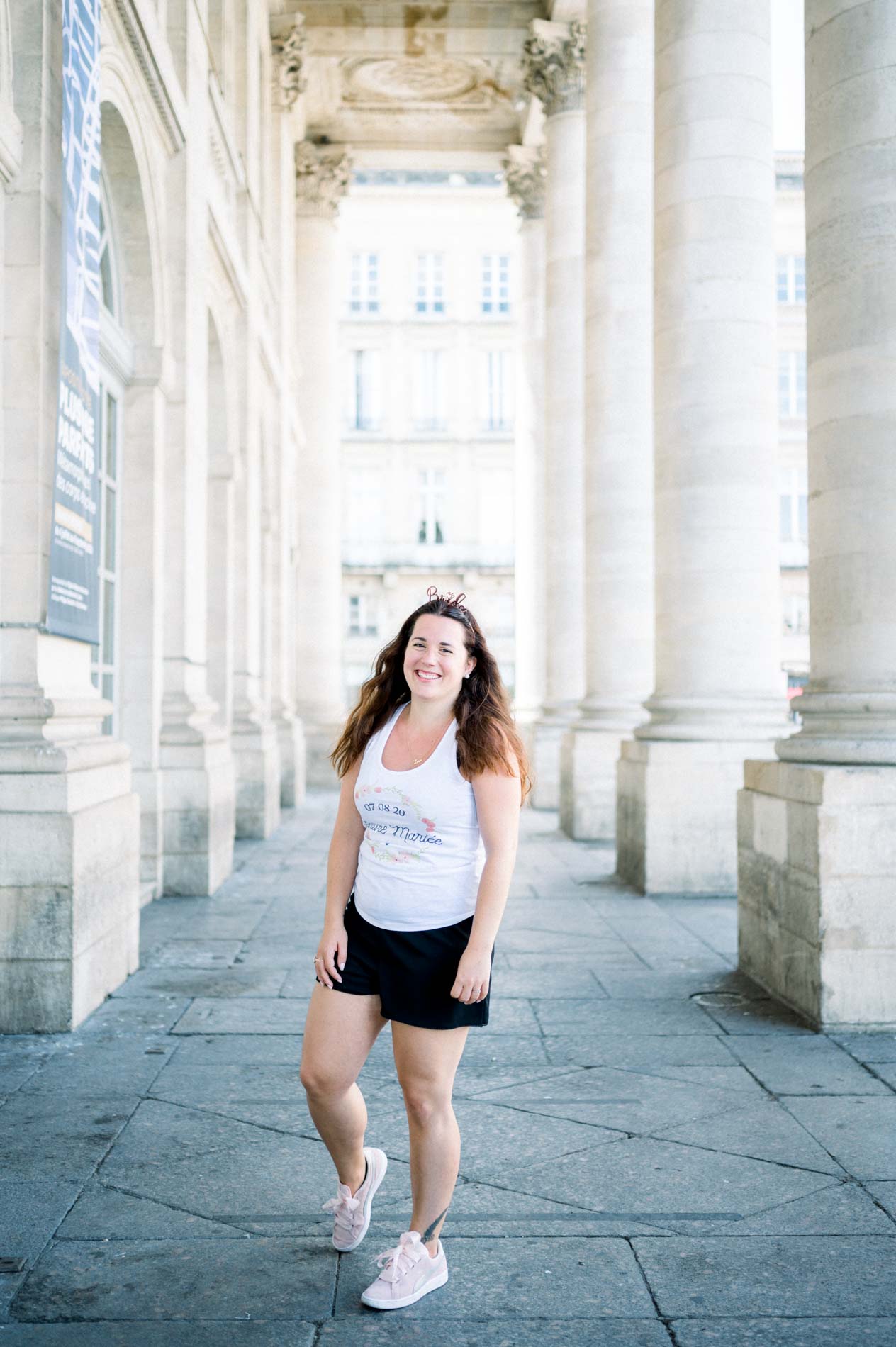 The smiling bride-to-be walking between the columns during her hen party