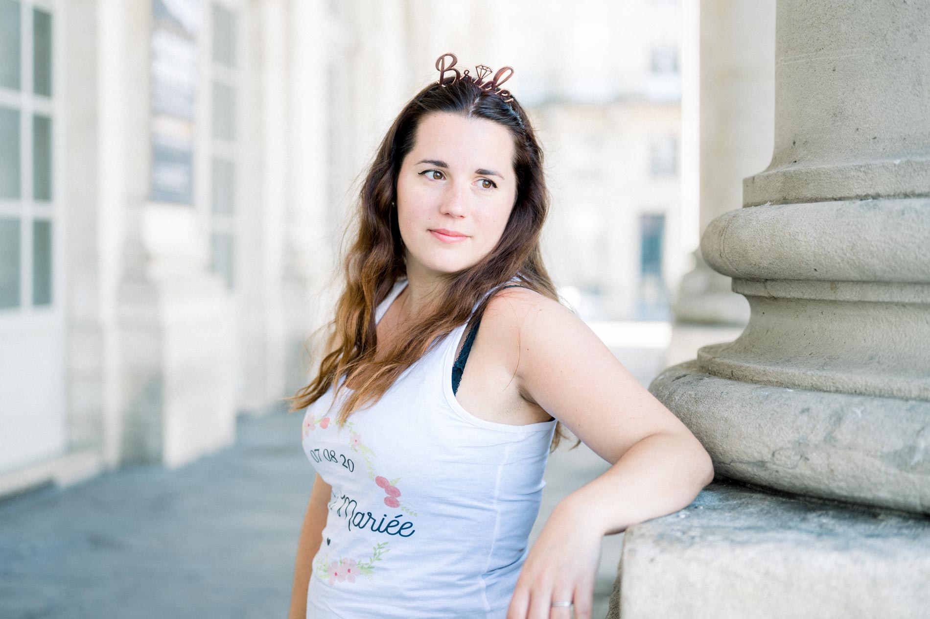 Portrait of the bride-to-be in a hen party tank top leaning on a column