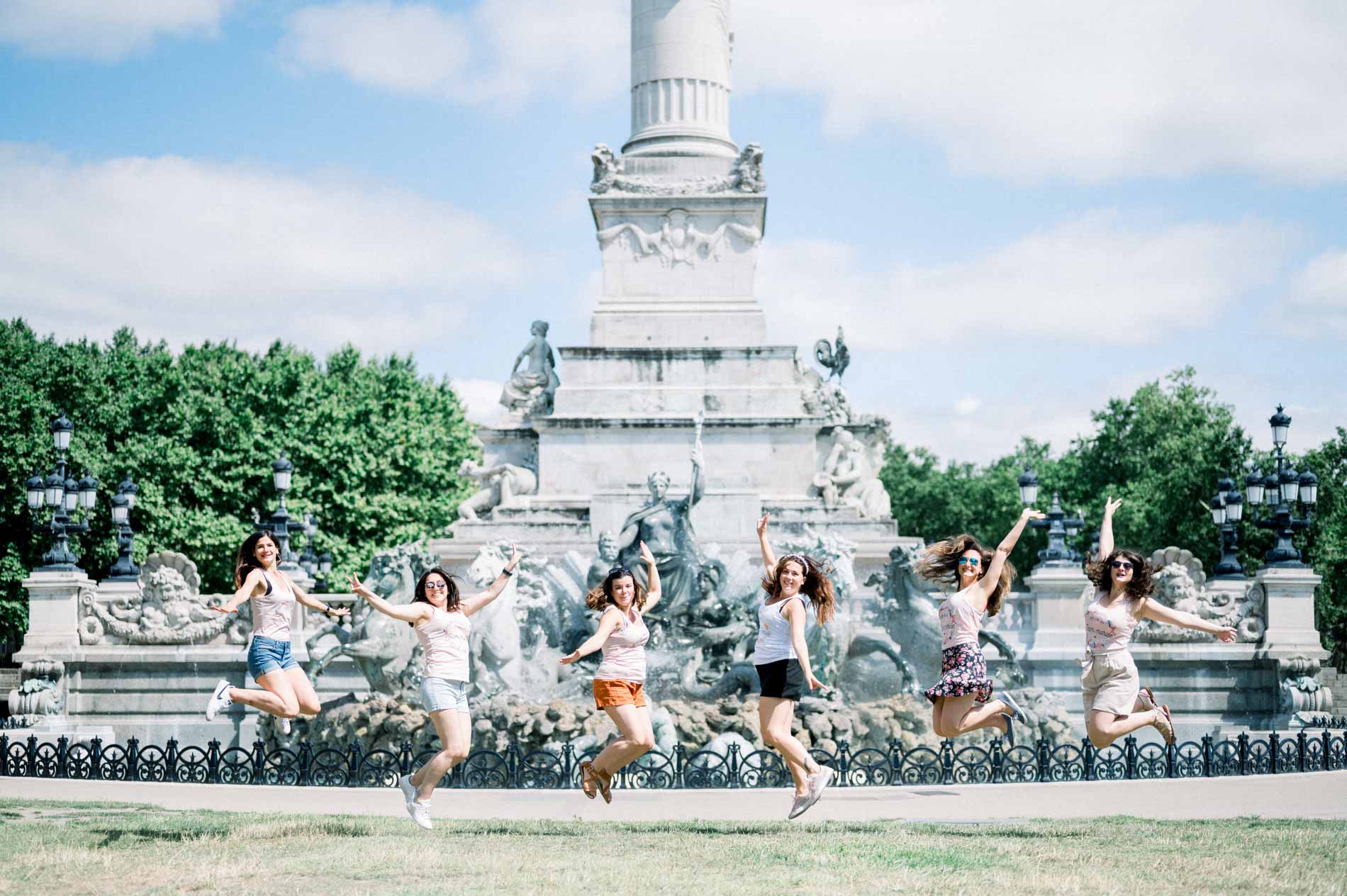 Hen party friends leaping in front of the Girondins monument fountains