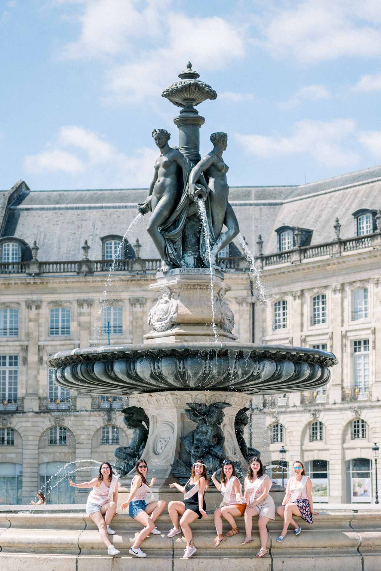 The hen party friends sitting on the rim of the Bourse fountain