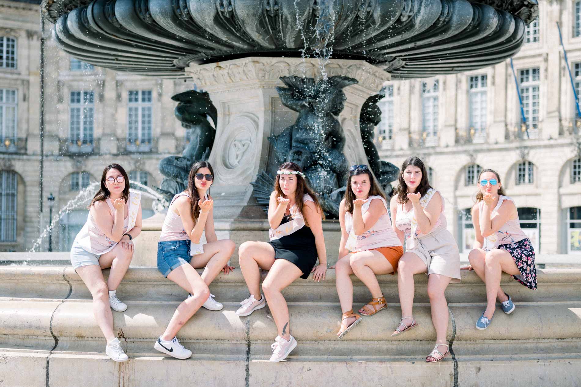 Hen party friends laughing on the edge of the fountain, close-up