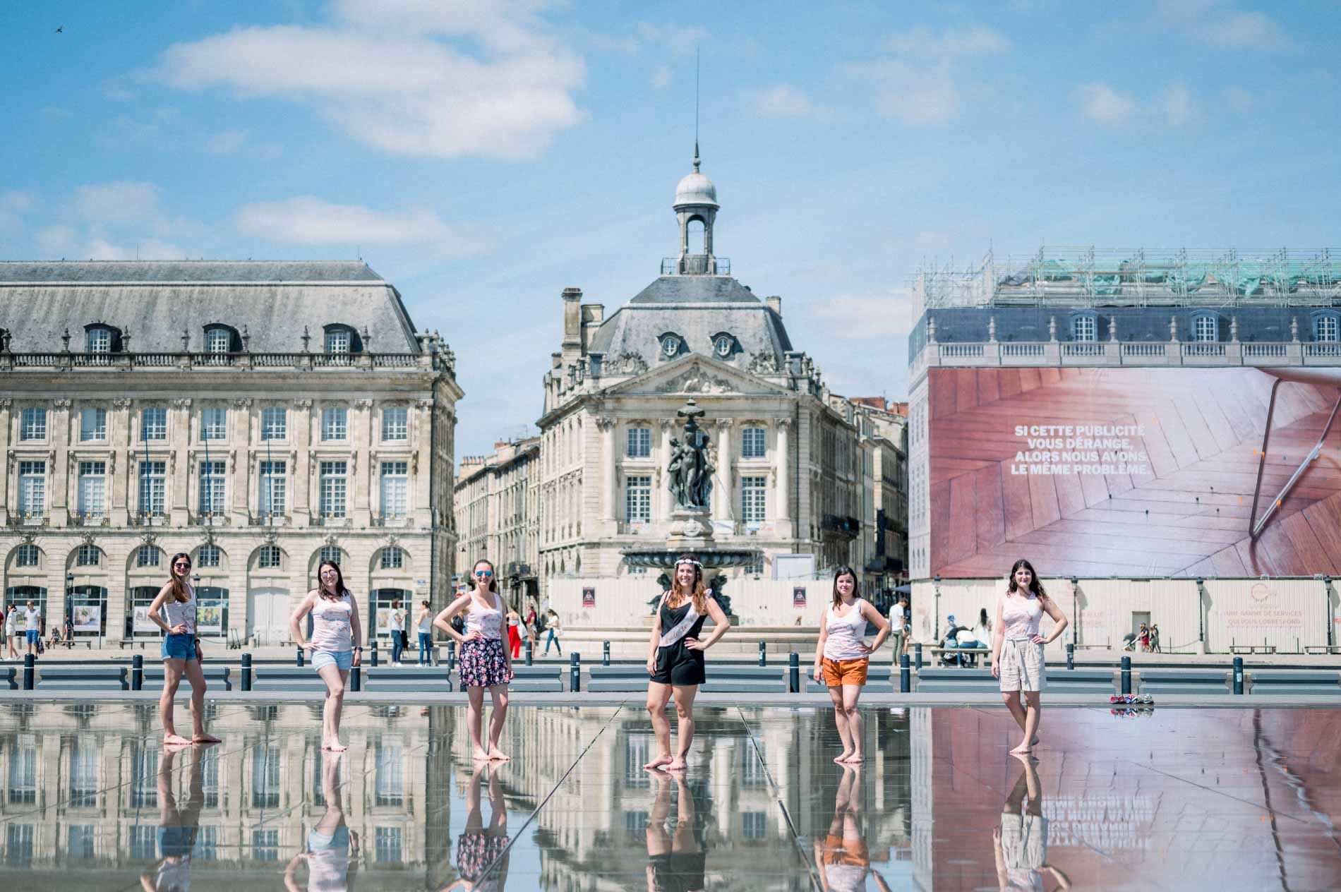 Hen party friends lined up on the water mirror facing the Bordeaux façades