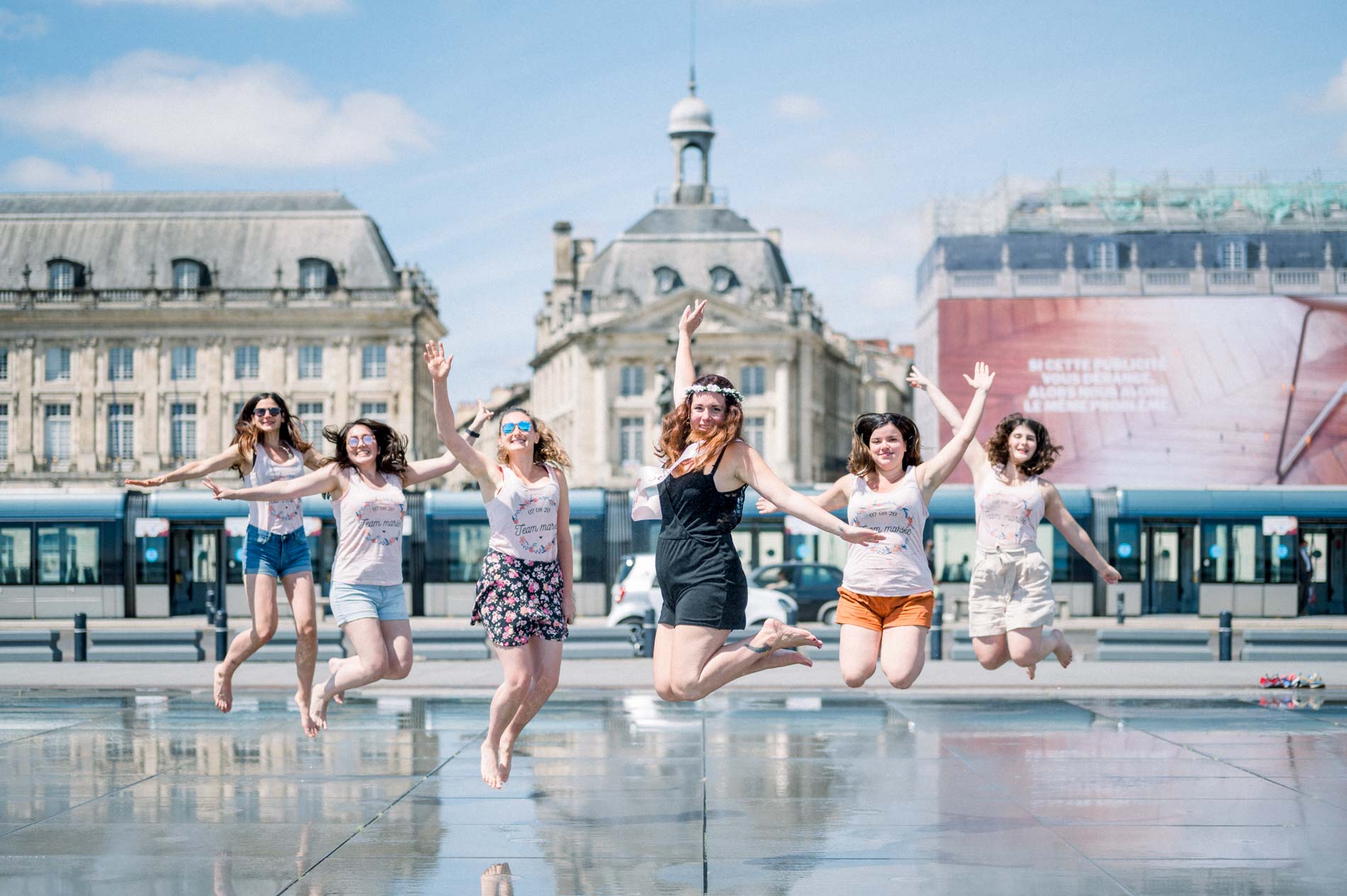 The friends jumping for joy on the water mirror before the Bourse façades