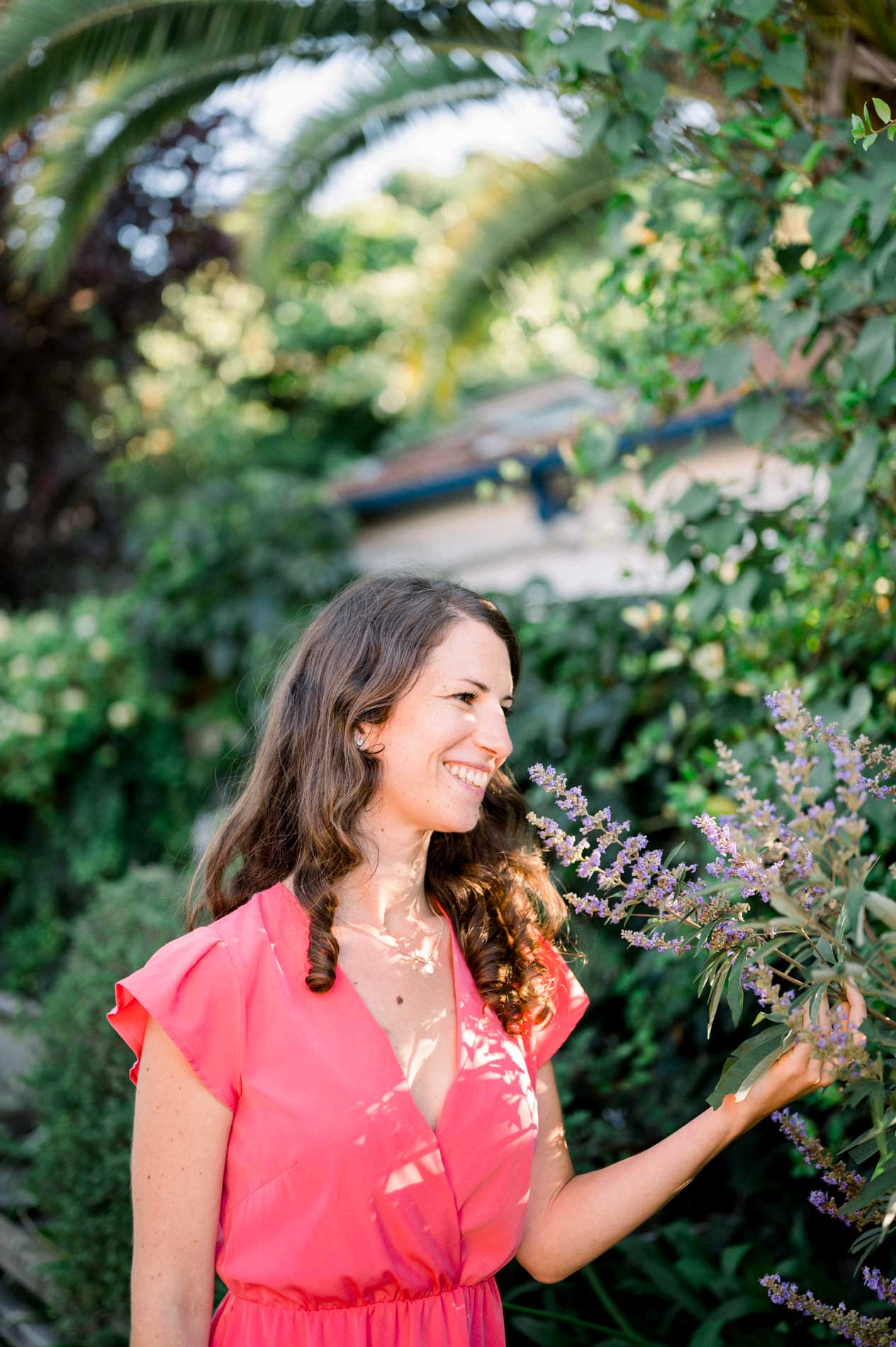 The bride-to-be smelling a sprig of lavender in a flower-filled garden