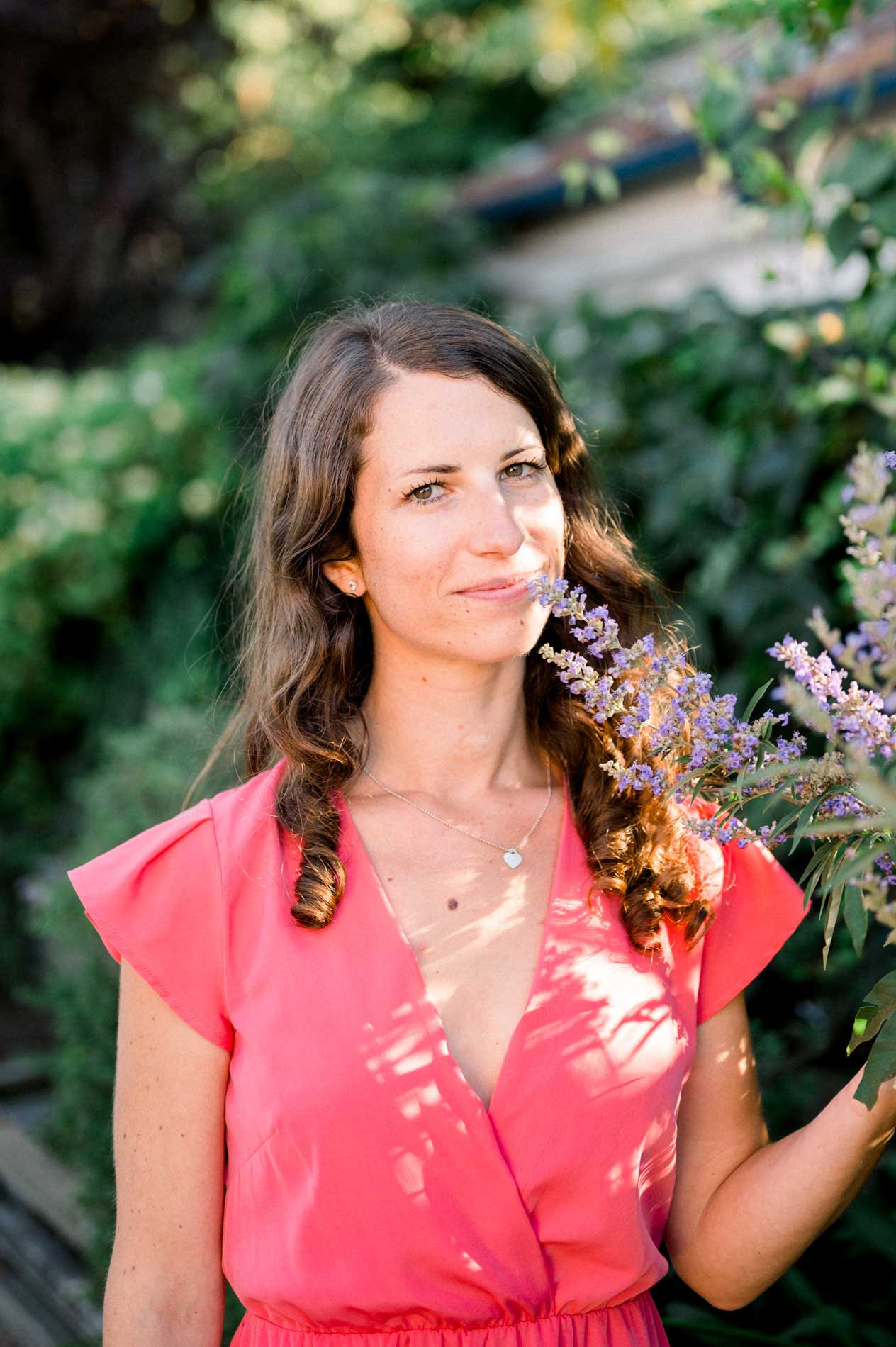 Portrait of the bride-to-be in a coral dress beside a lavender bush