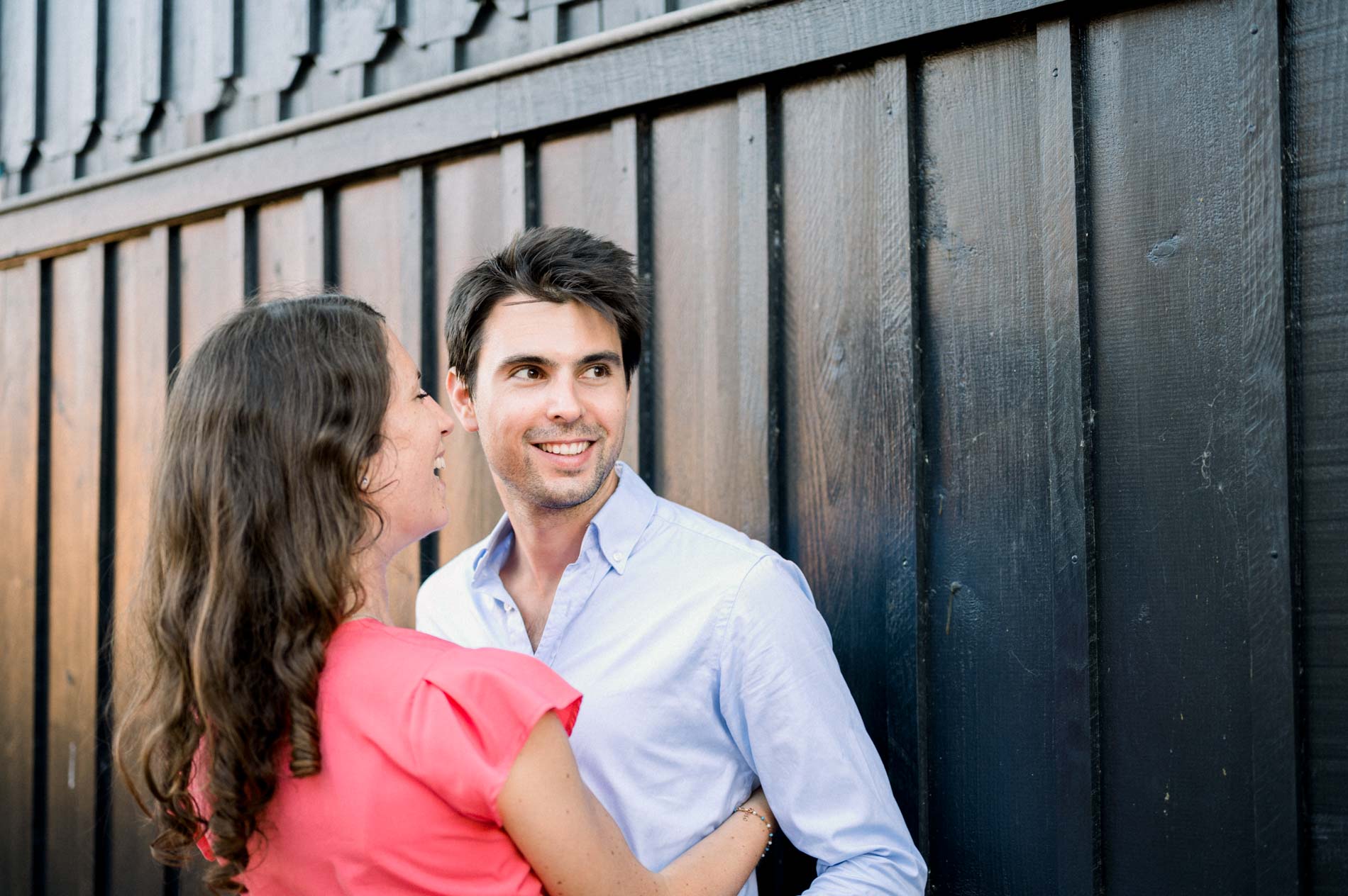 The couple smiling against the black boards of an oyster hut
