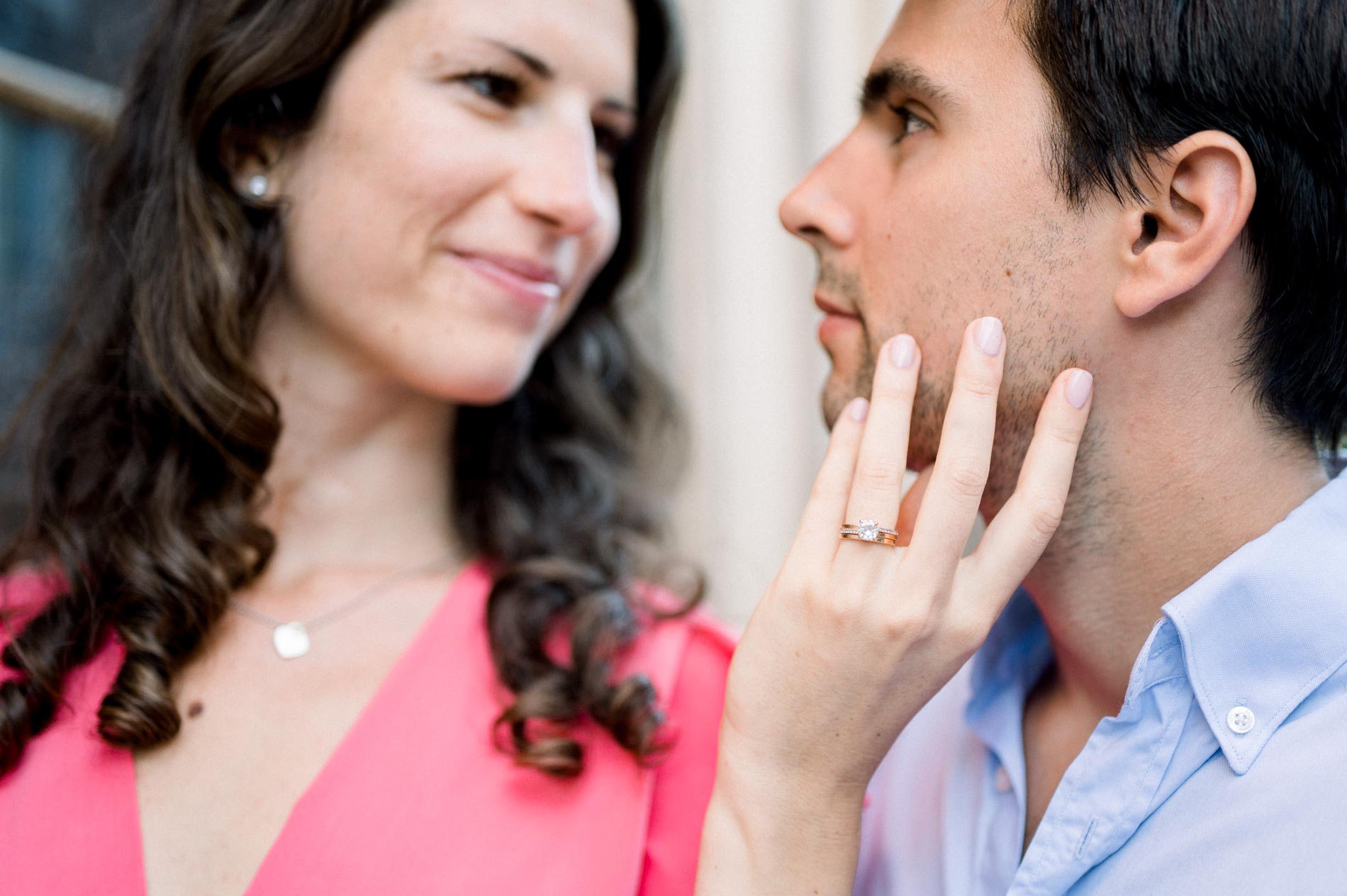 The bride-to-be touches her fiancé's face, engagement ring on her finger
