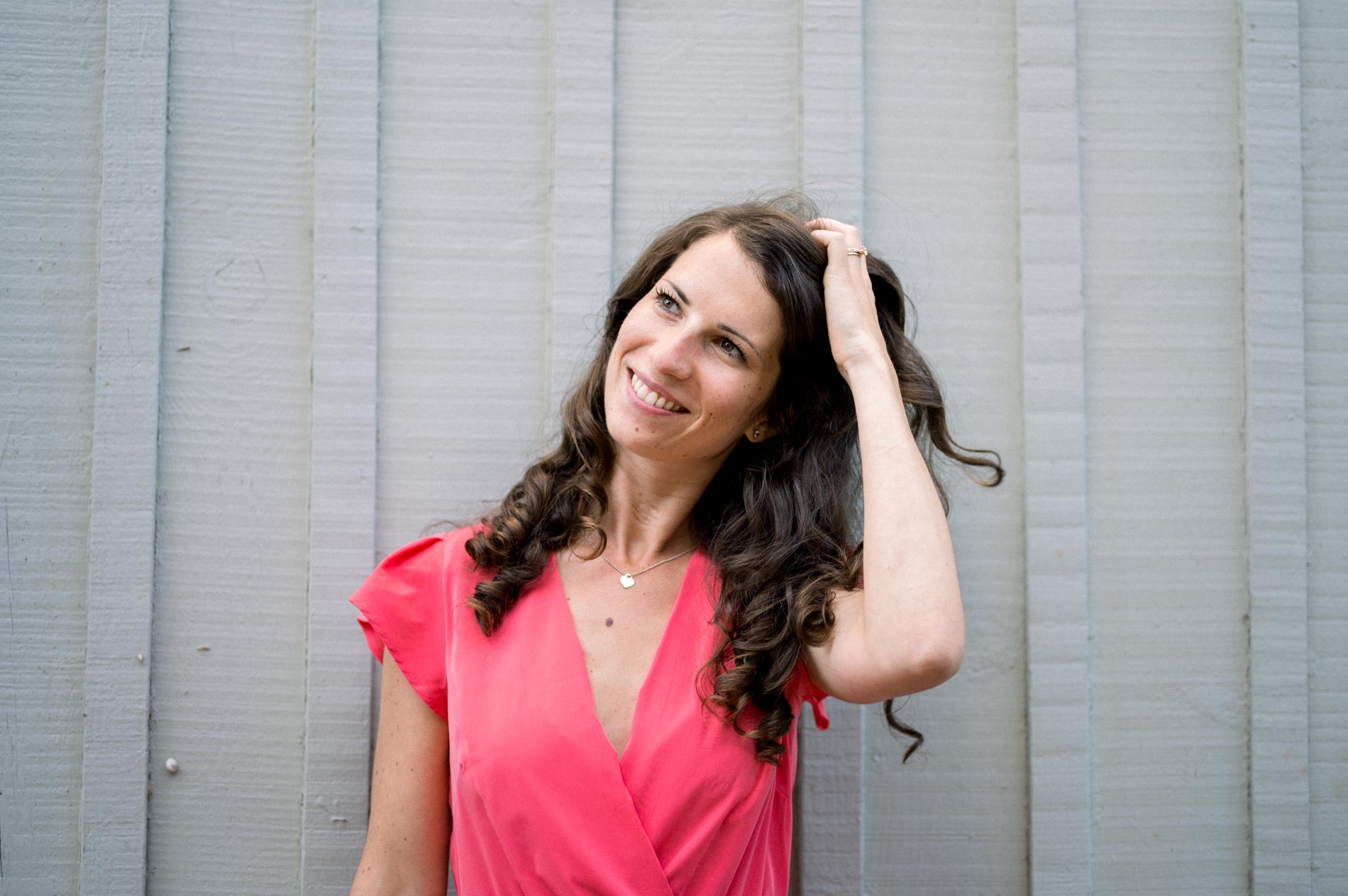 The bride-to-be running a hand through her hair against a grey wooden hut