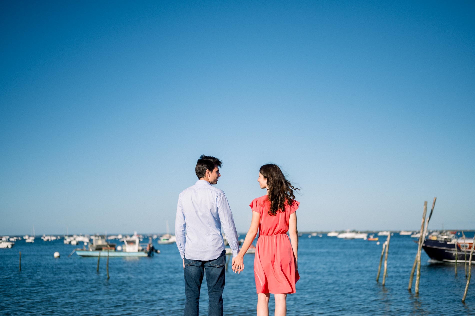 The couple hand in hand looking out over Arcachon Bay and its boats