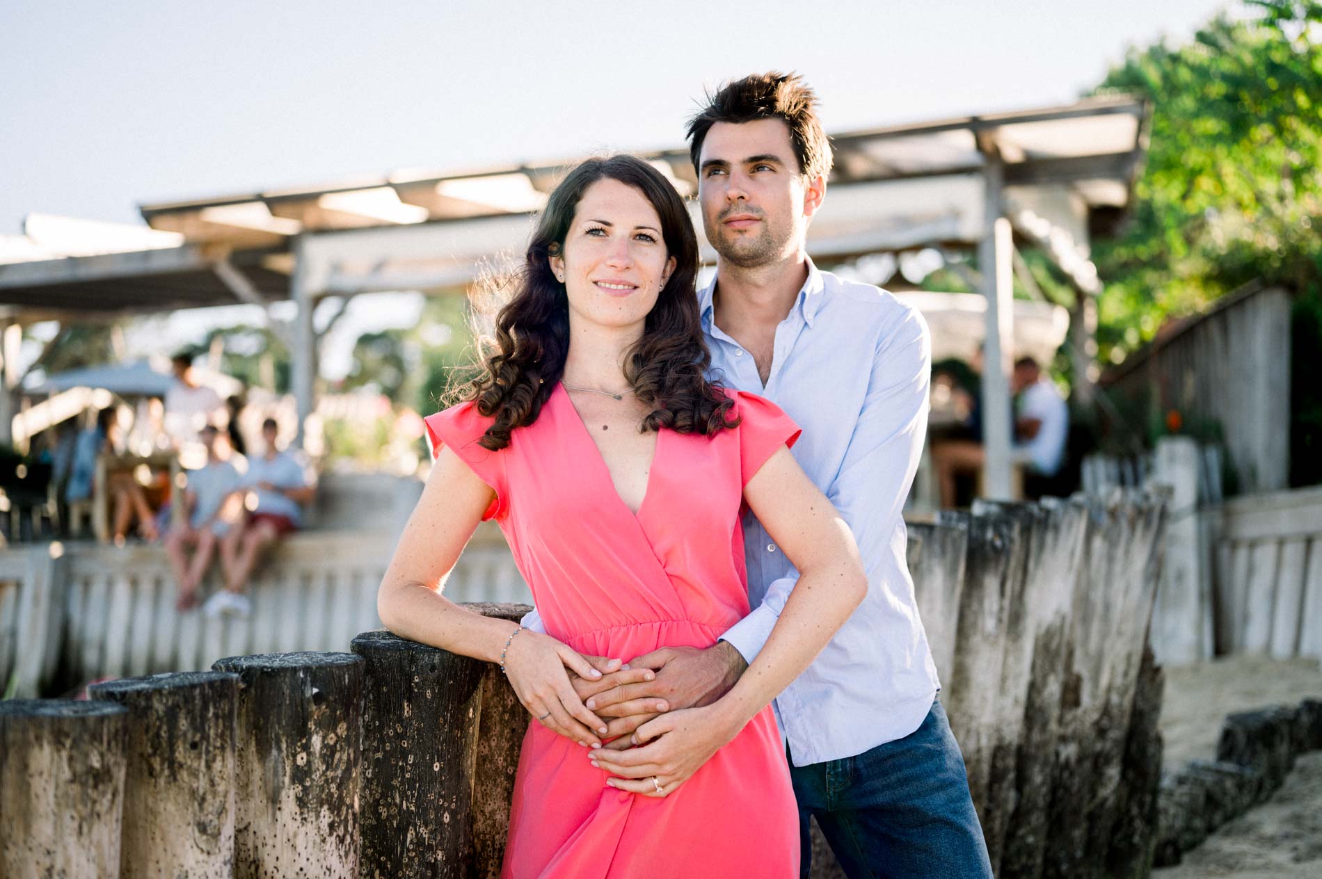 The fiancé holds the bride-to-be on a wooden jetty in the oyster village