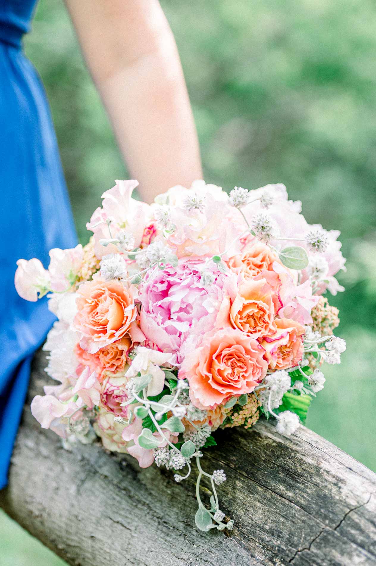 Bouquet of peonies and peach roses resting on a fallen tree trunk