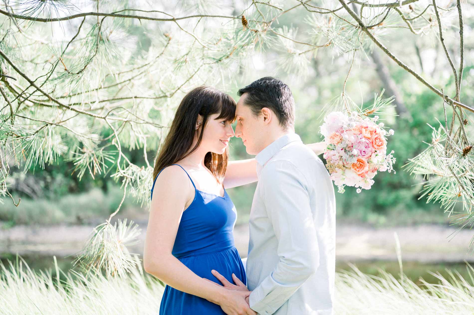 The couple forehead to forehead under the pines holding a peony bouquet, Cap Ferret