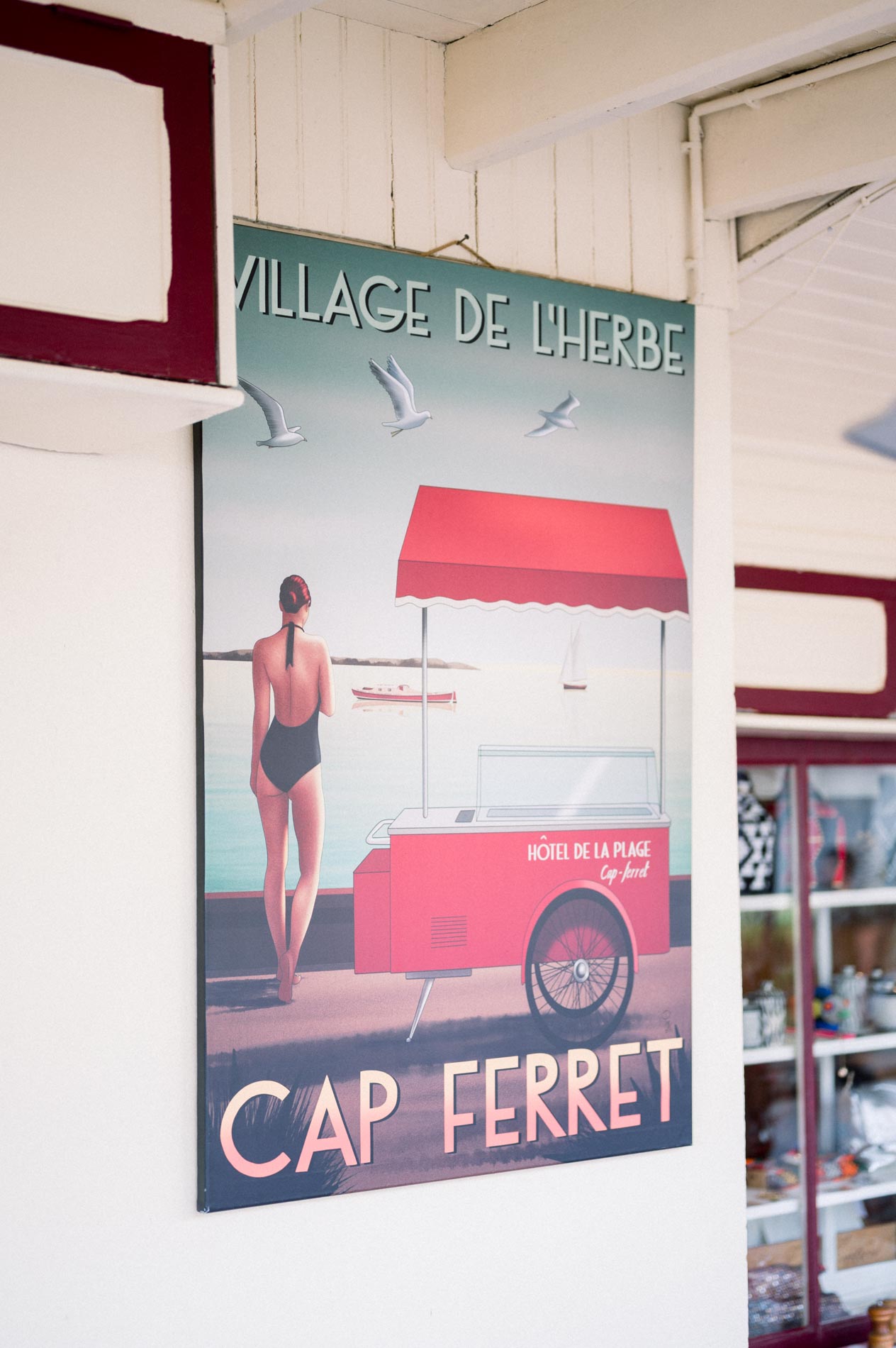 Vintage “Village de l'Herbe – Cap Ferret” poster hanging on a cabin