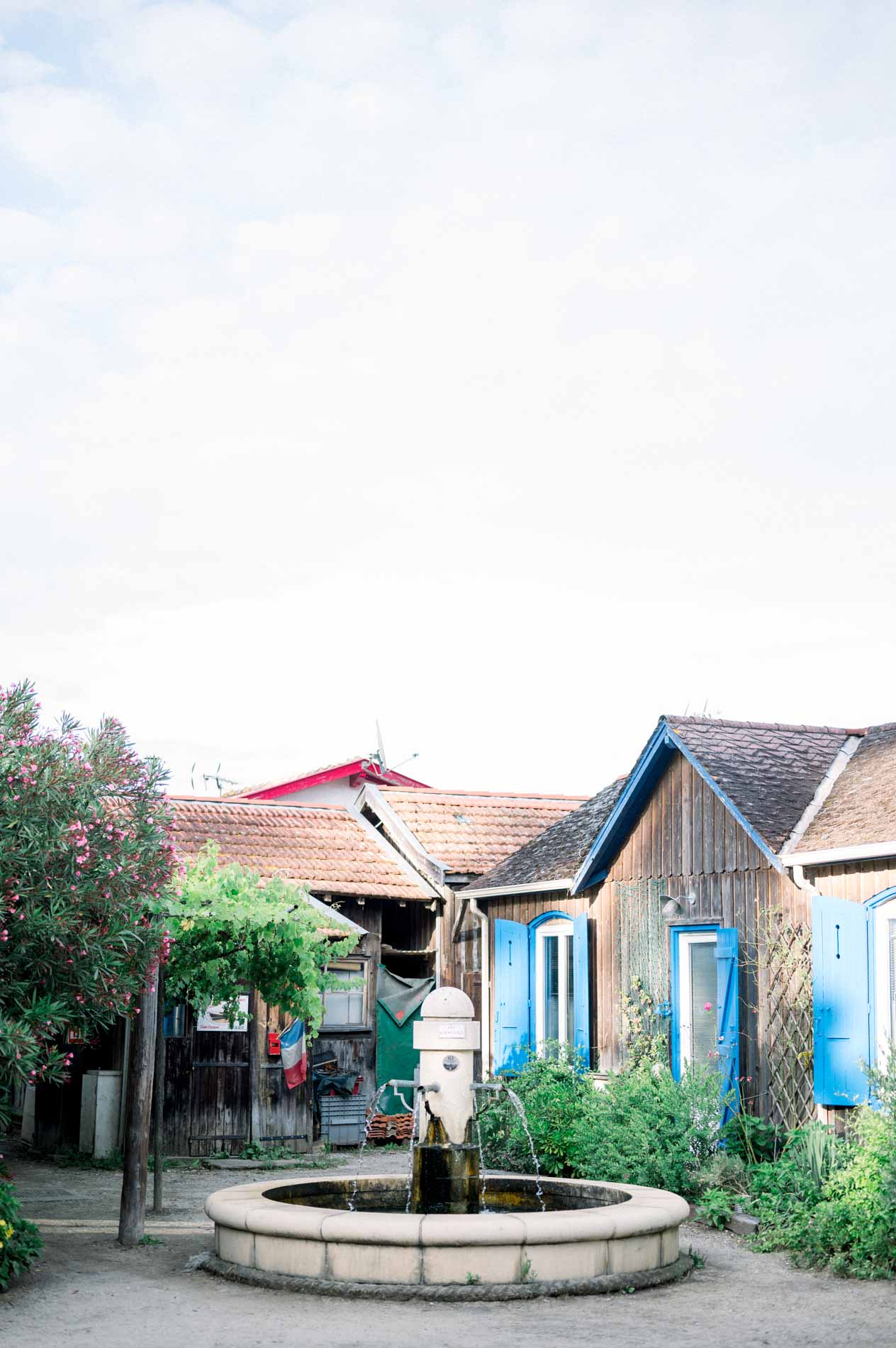 Fountain and colourful cabins in the village of L'Herbe on Cap Ferret