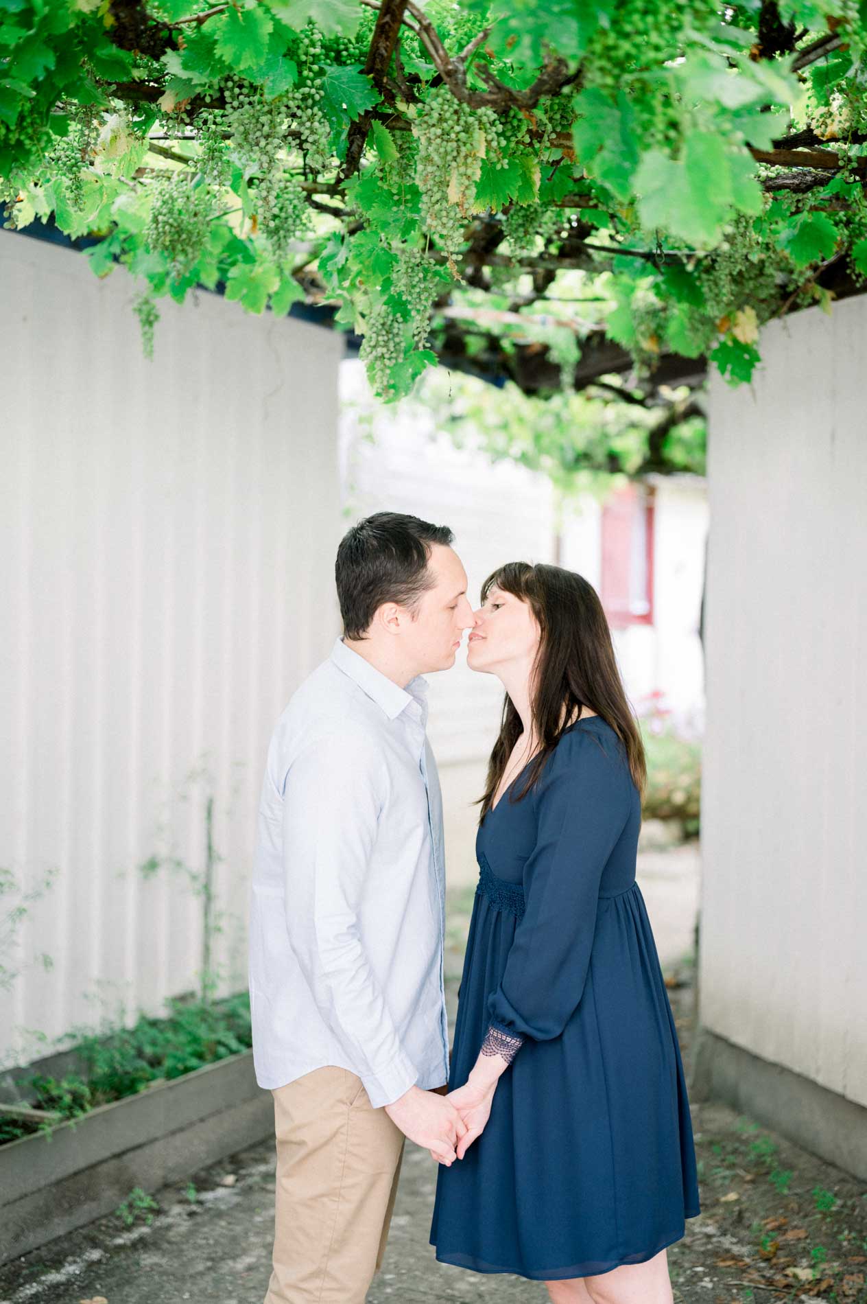 The engaged couple kiss under the vine arbour of a lane in L'Herbe