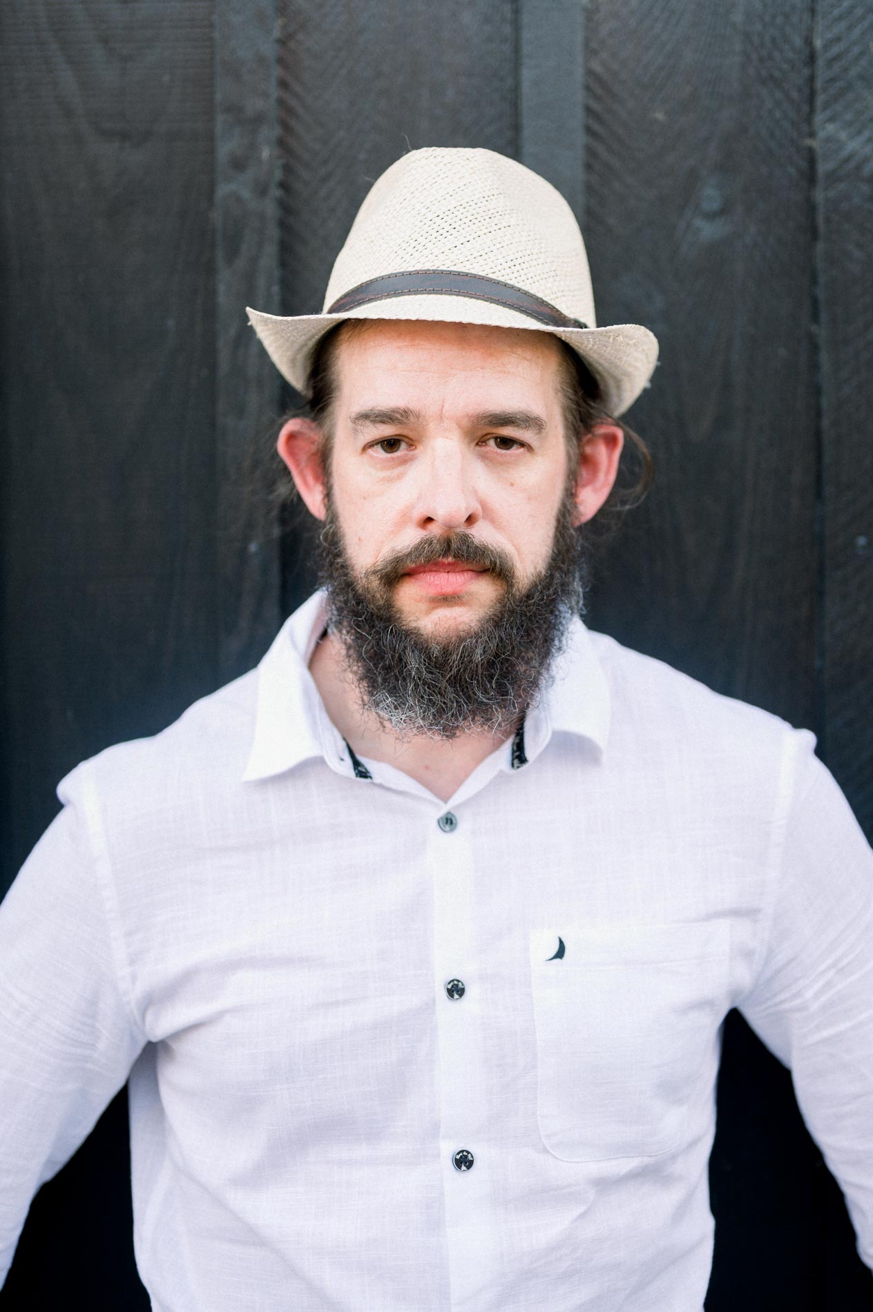 Portrait of the bearded man in a straw hat against a black wall