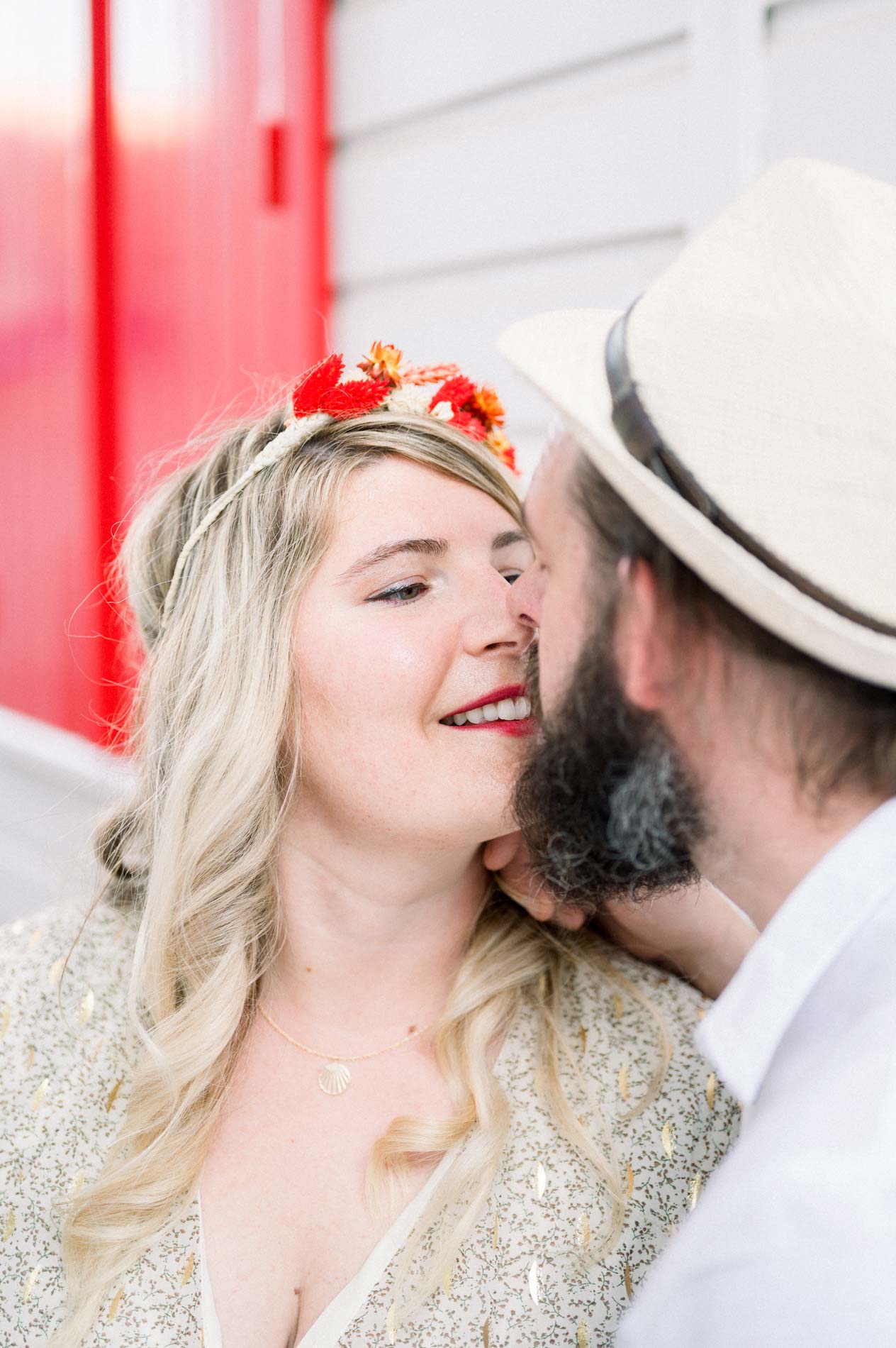 Derek kissing Julie's cheek beside a red and white cabin