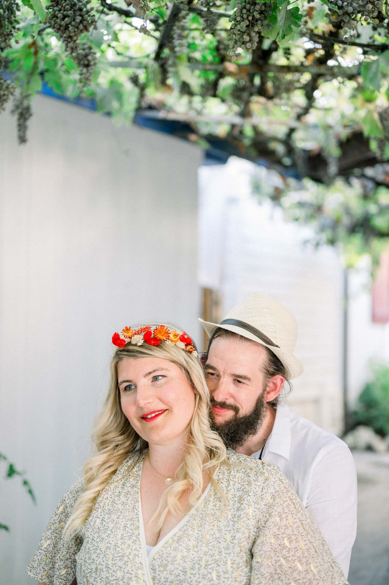 The couple embracing in a lane of cabins beneath a vine trellis