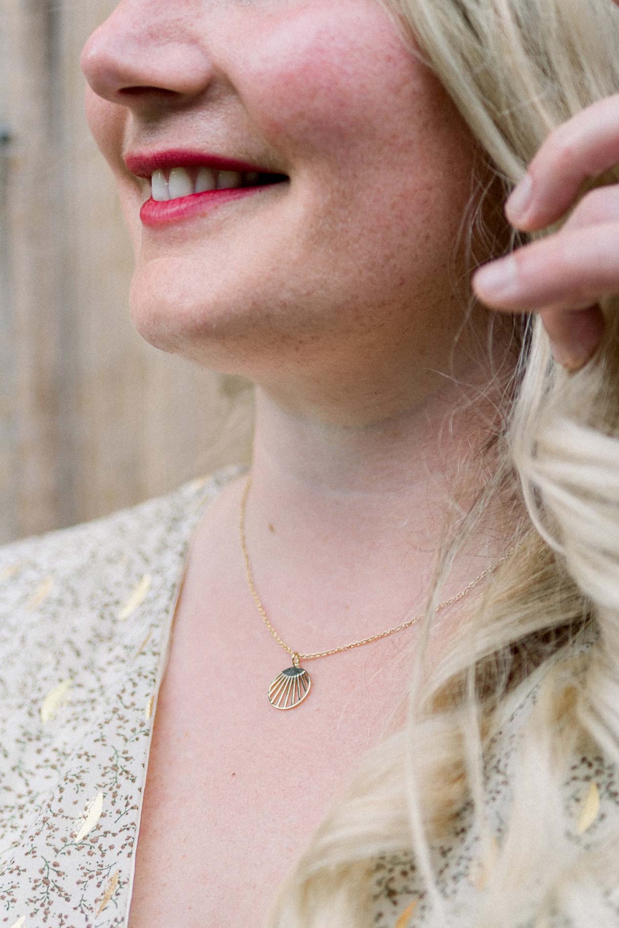 Close-up of the woman's smile and gold necklace, blonde hair