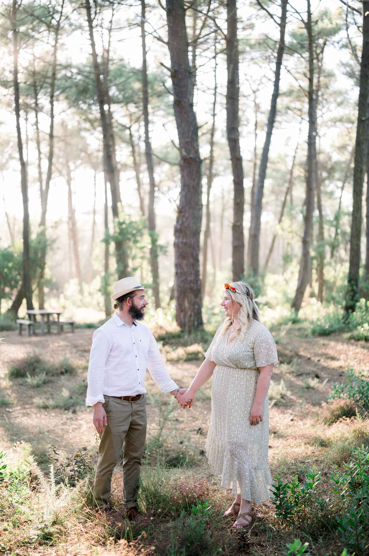 The couple holding hands in the middle of the pine forest