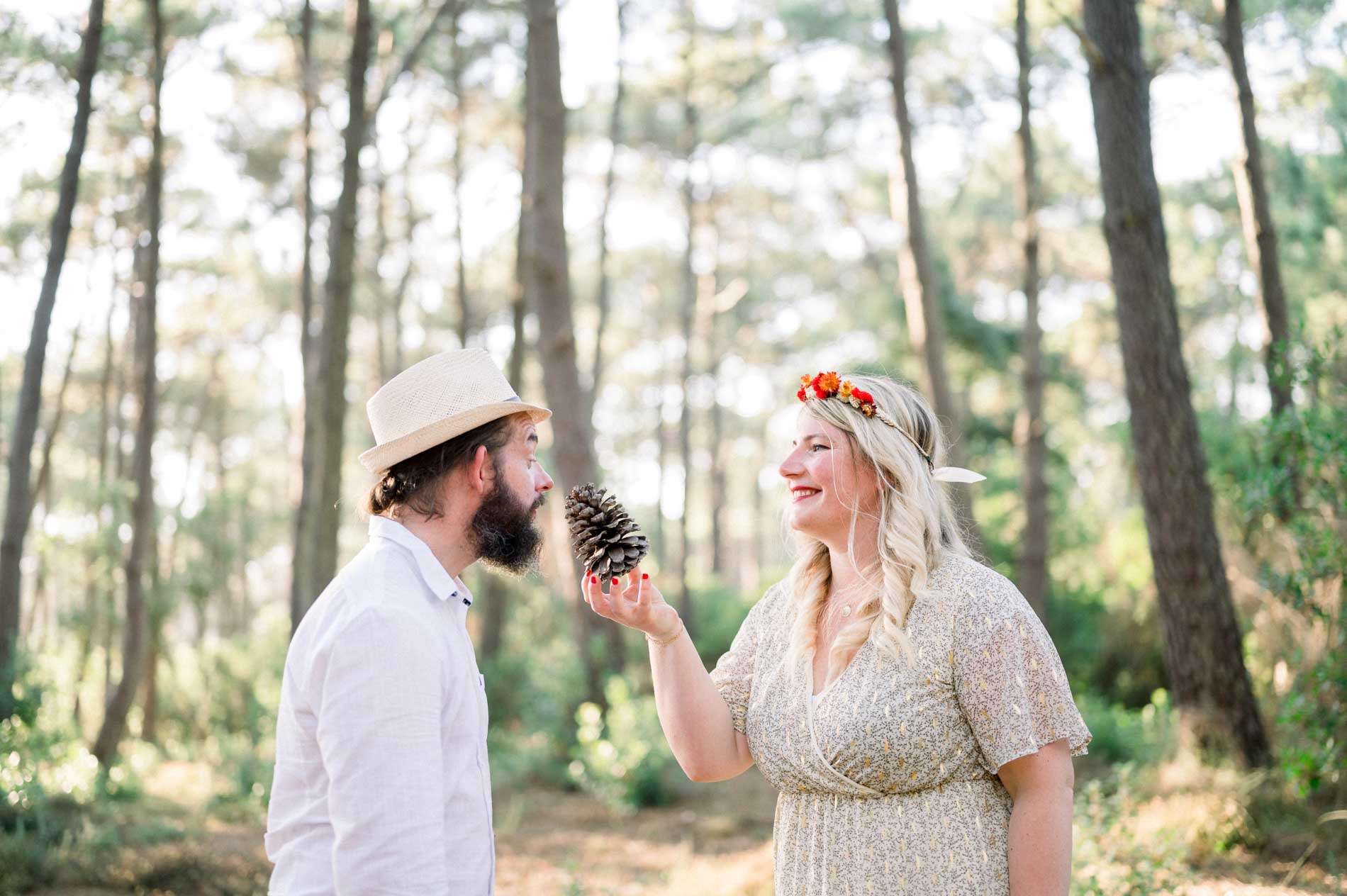 Julie playfully holding a pine cone up to Derek in the pine forest