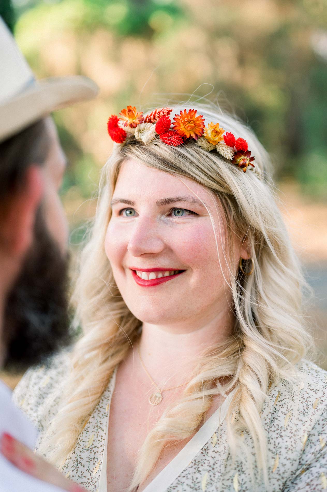 Portrait of the smiling woman in a red flower crown in the pine forest