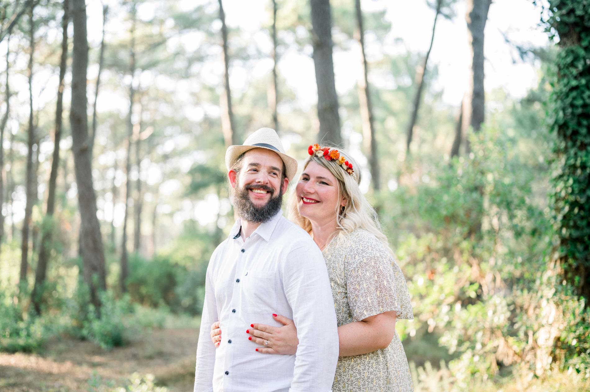 The smiling couple embracing at the edge of the pine forest