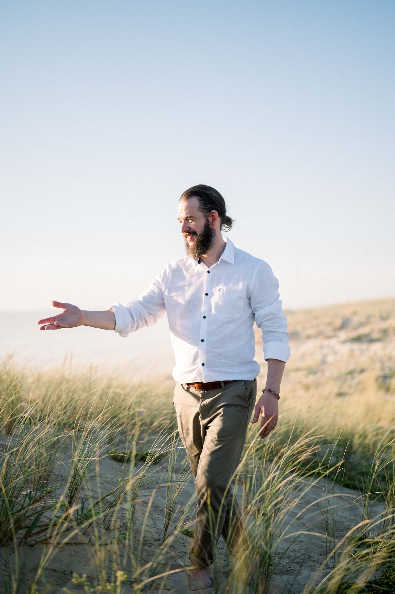 Derek walking through the dune, reaching out his hand towards Julie