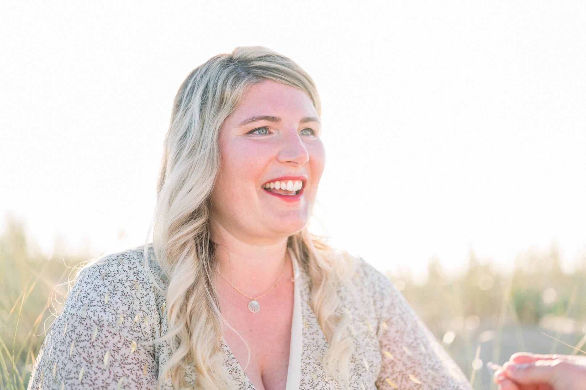 Julie beaming as she sees the ring, sitting in the dunes