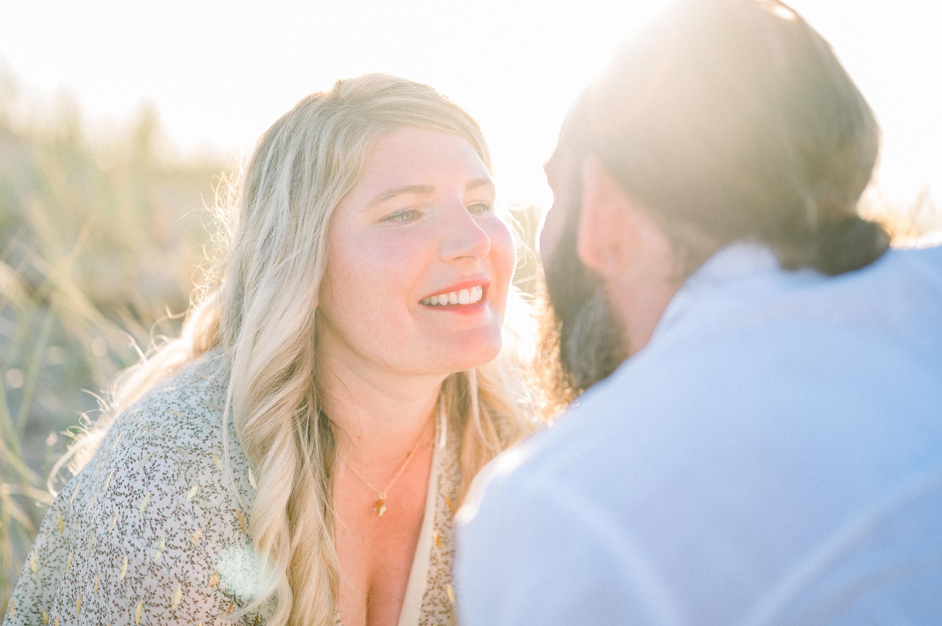 The couple face to face and smiling in the dune grass