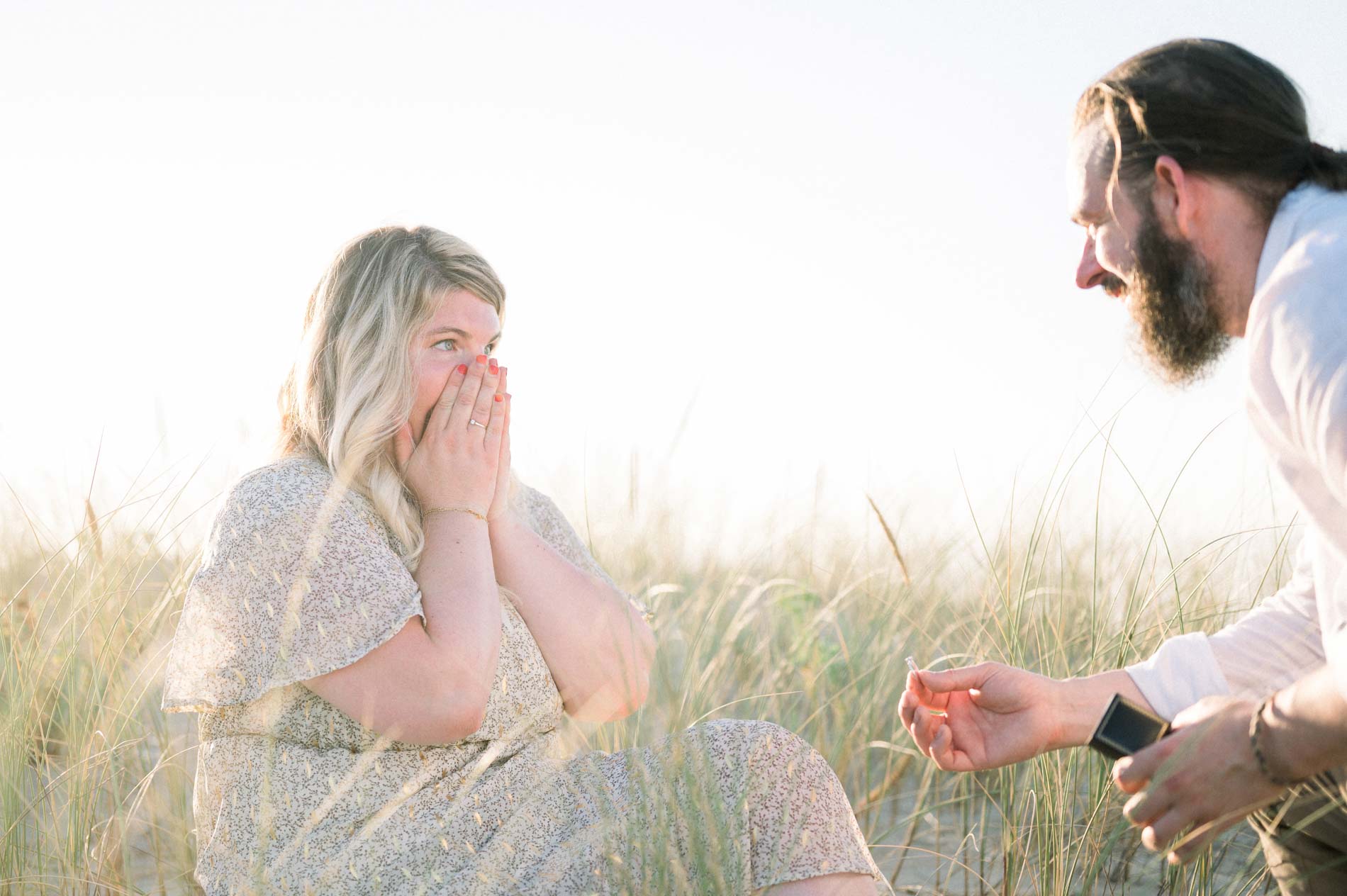 Julie covering her mouth, overwhelmed by the beach proposal