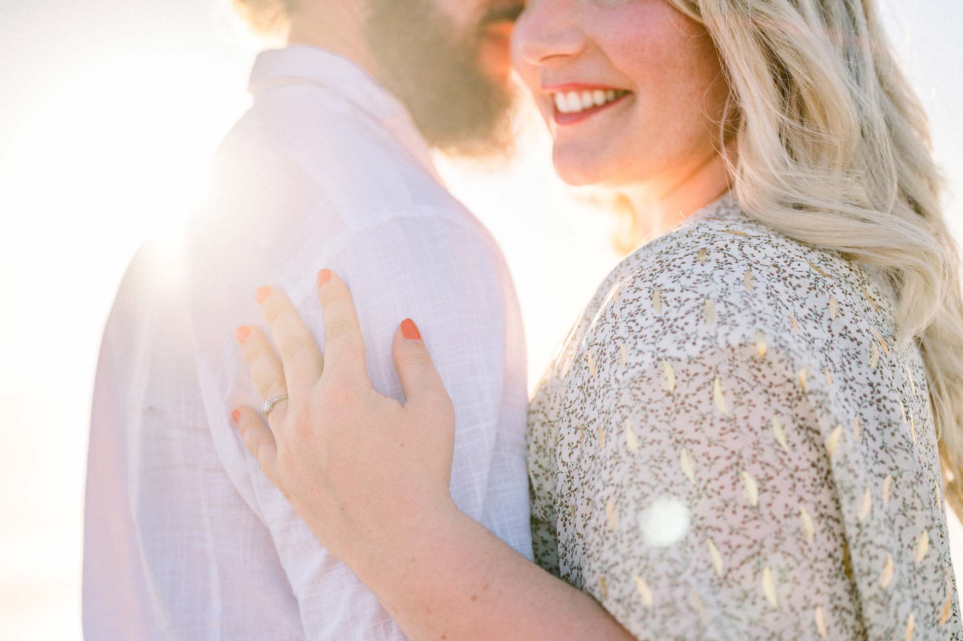 Julie's ringed hand on Derek's shirt, backlit by the sun