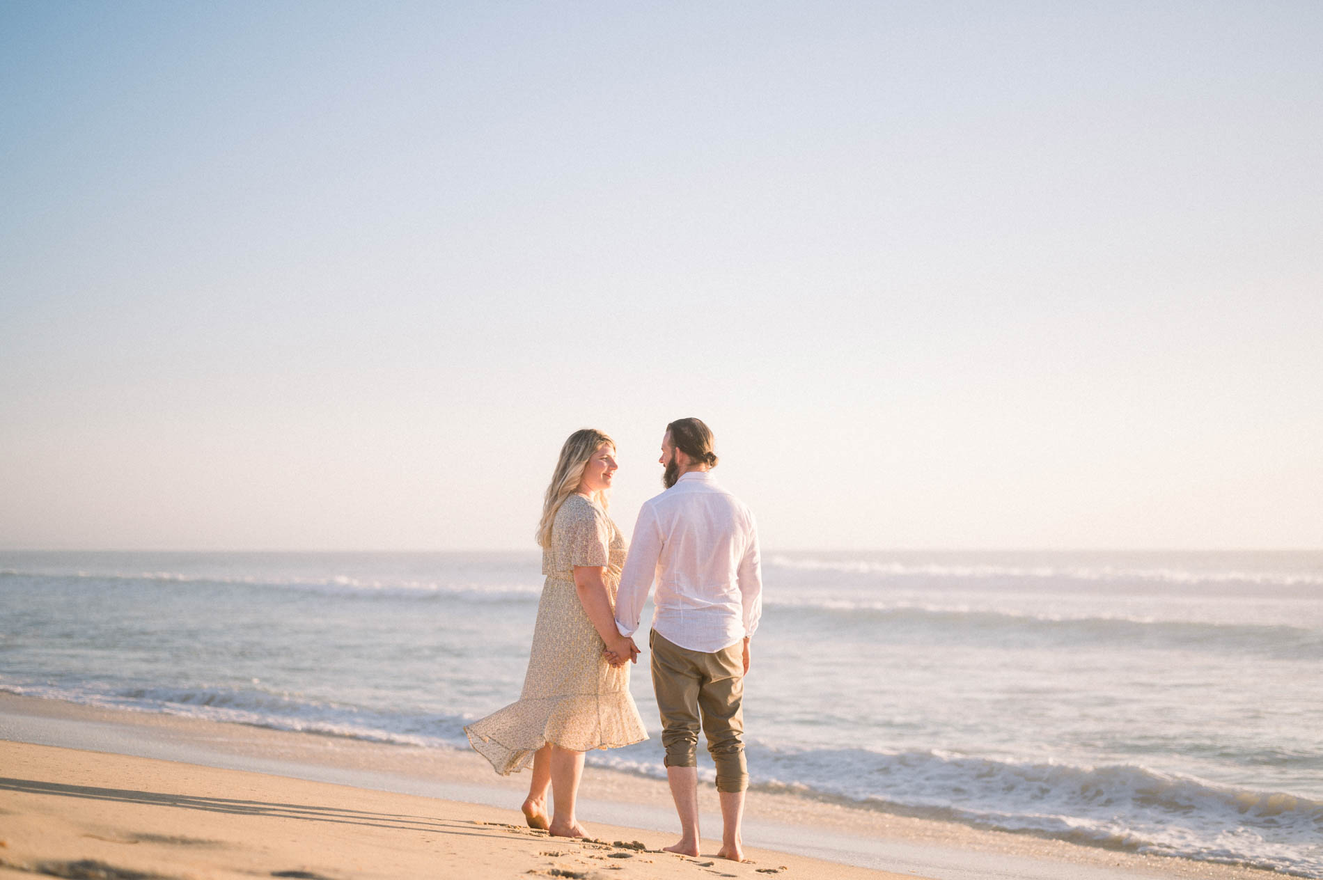 The fiancés strolling along the water's edge on the beach