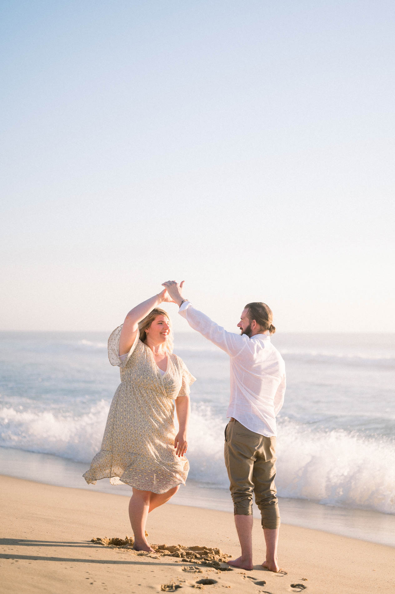 Derek twirling Julie at the water's edge on the beach