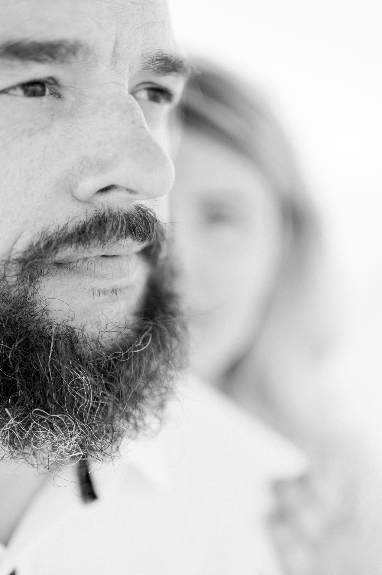 Black and white portrait of the bearded man, his fiancée blurred behind him