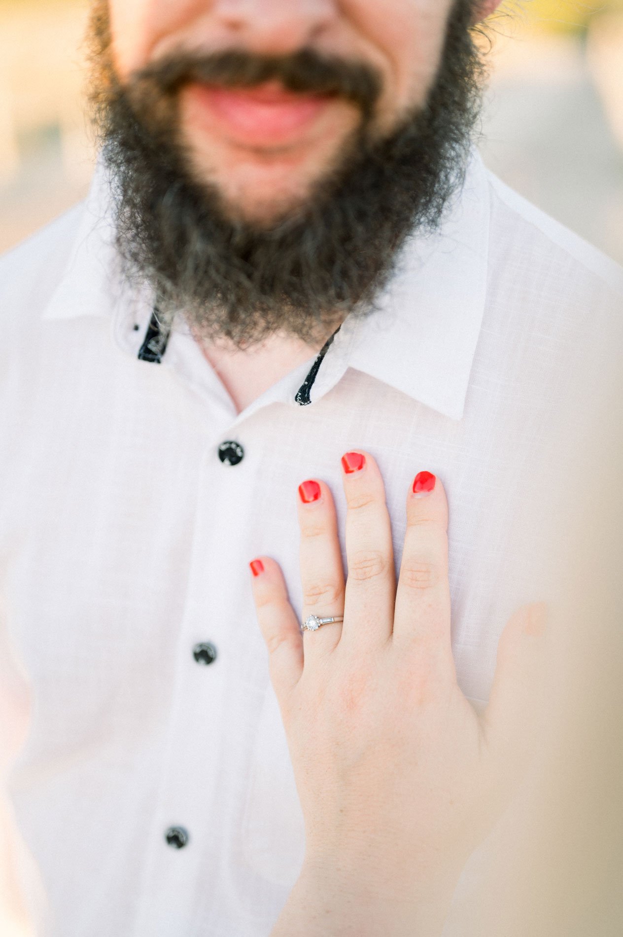 Ringed hand with red nails on Derek's white shirt