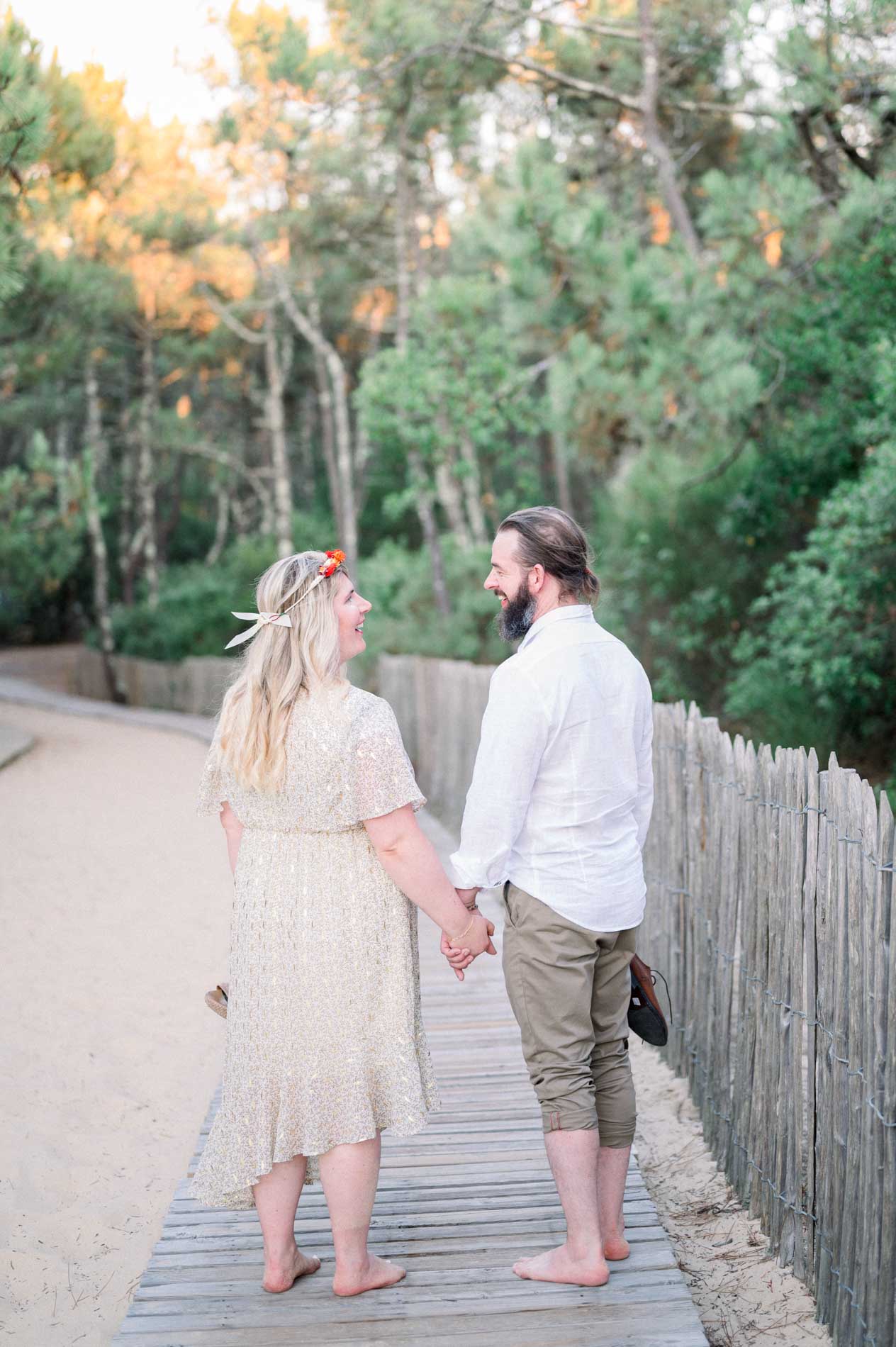 The fiancés walking hand in hand along the dune boardwalk