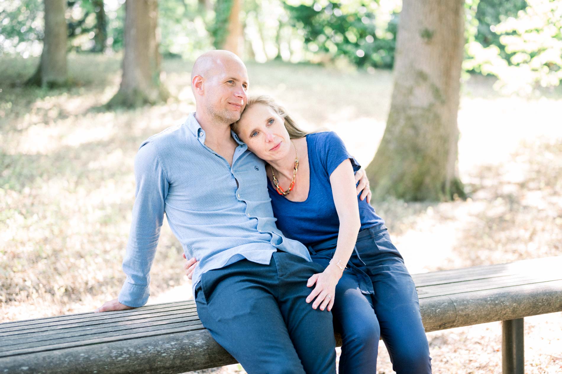 The parents sitting on a bench, her head resting on his shoulder