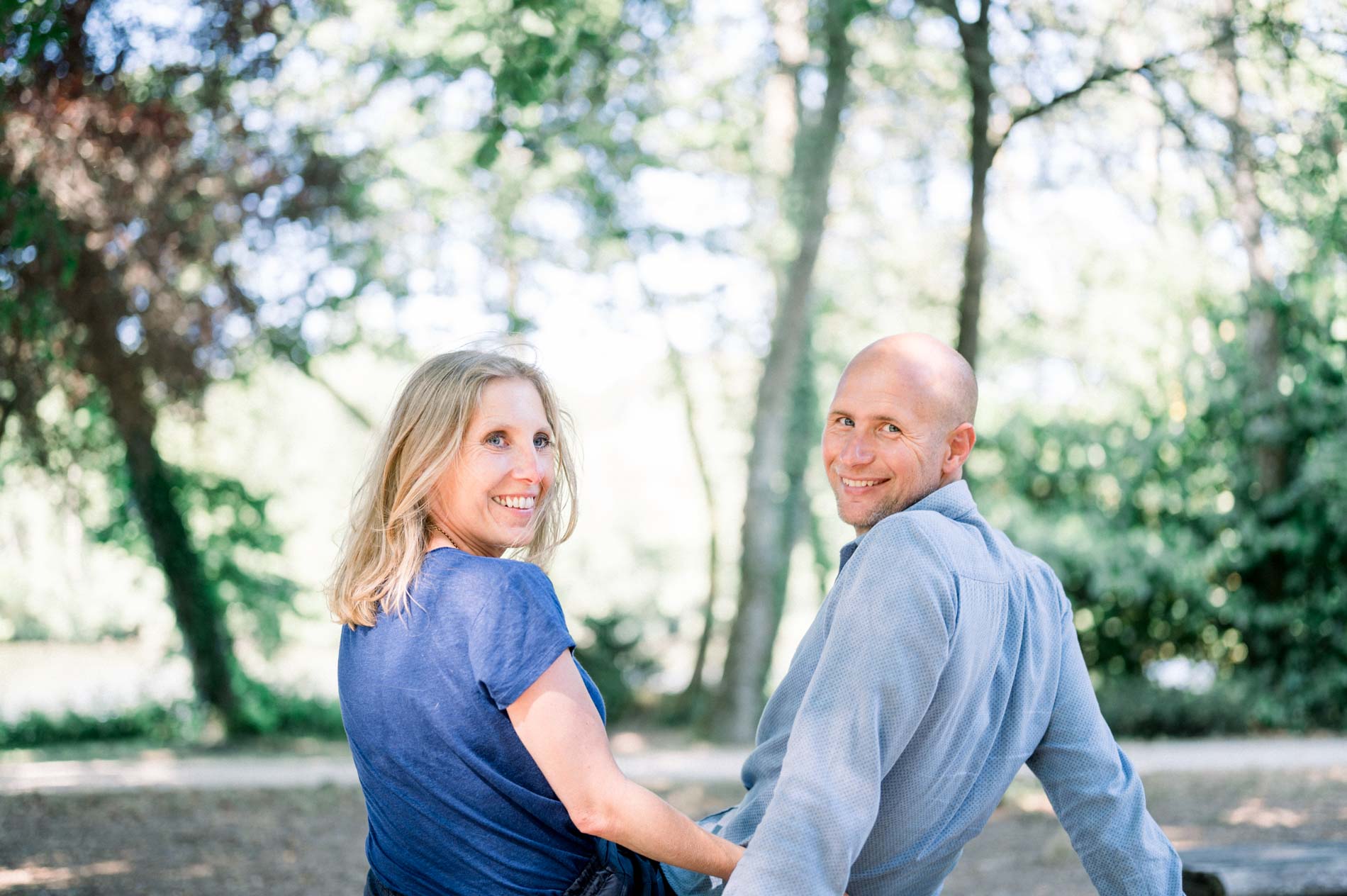 The parents sitting side by side sharing a smiling glance in the park