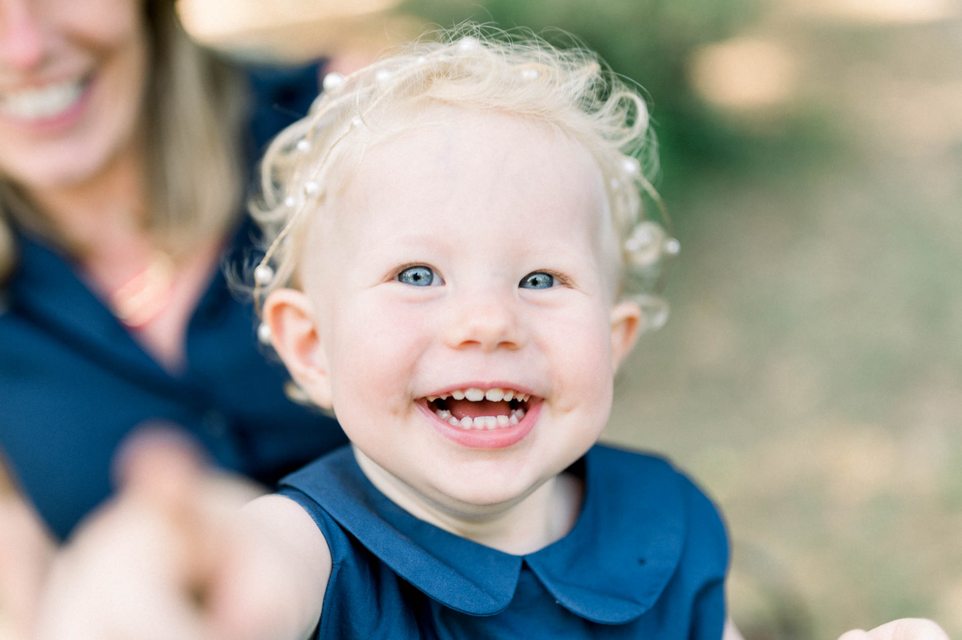 Curly-haired little girl bursting into laughter in her mum's arms