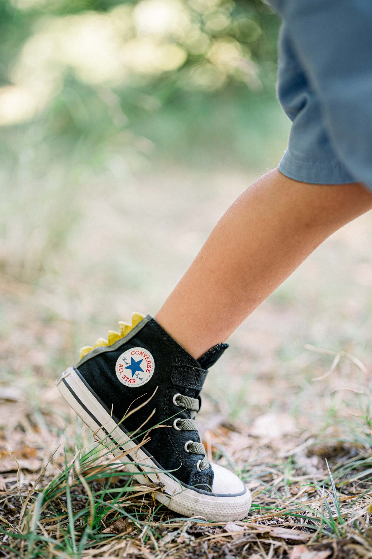 Close-up of a child's black sneaker running through the grass