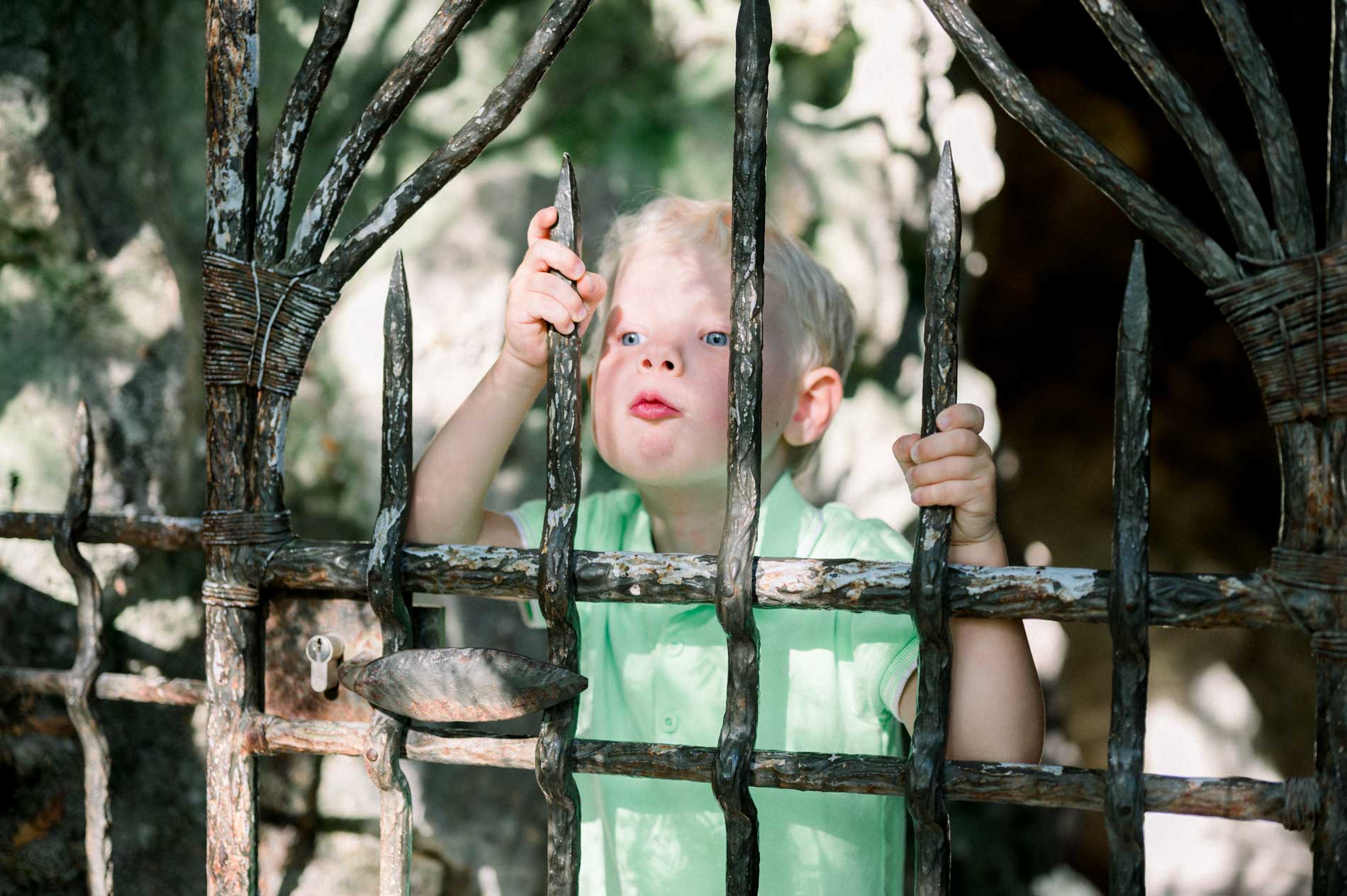 Little boy peering through an old iron gate