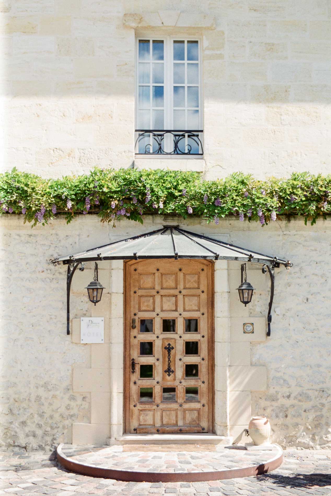 Porte d'entrée en bois sous marquise en fer forgé du Domaine de Larchey