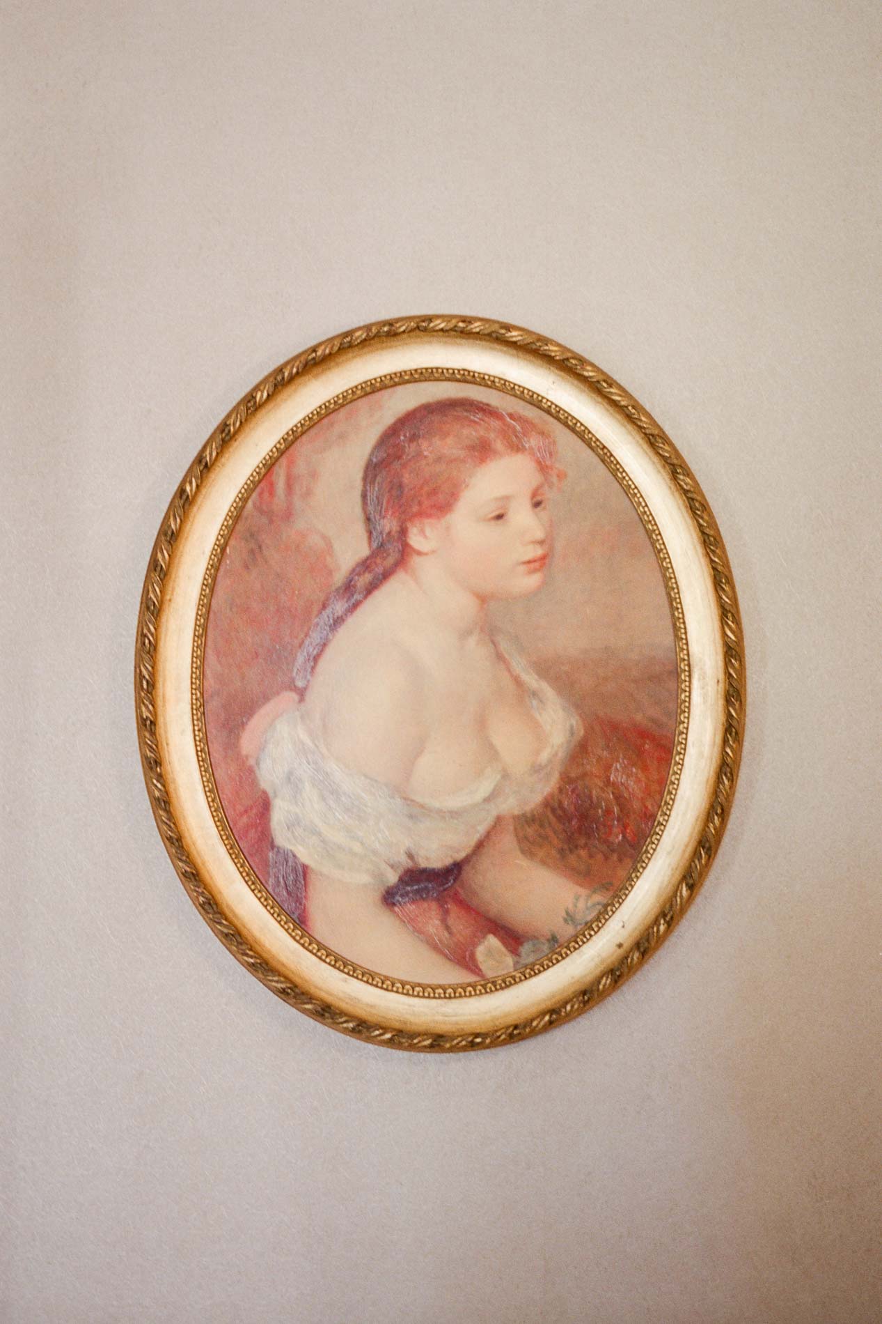 Tableau ancien dans un cadre ovale doré sur un mur clair du domaine