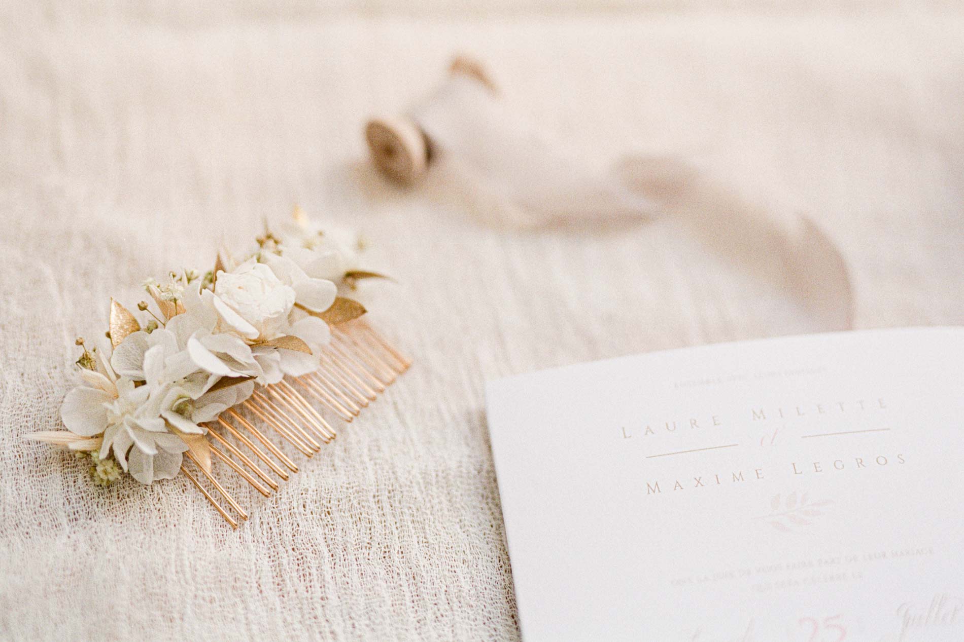 Peigne à cheveux fleuri de la mariée posé près du faire-part de mariage