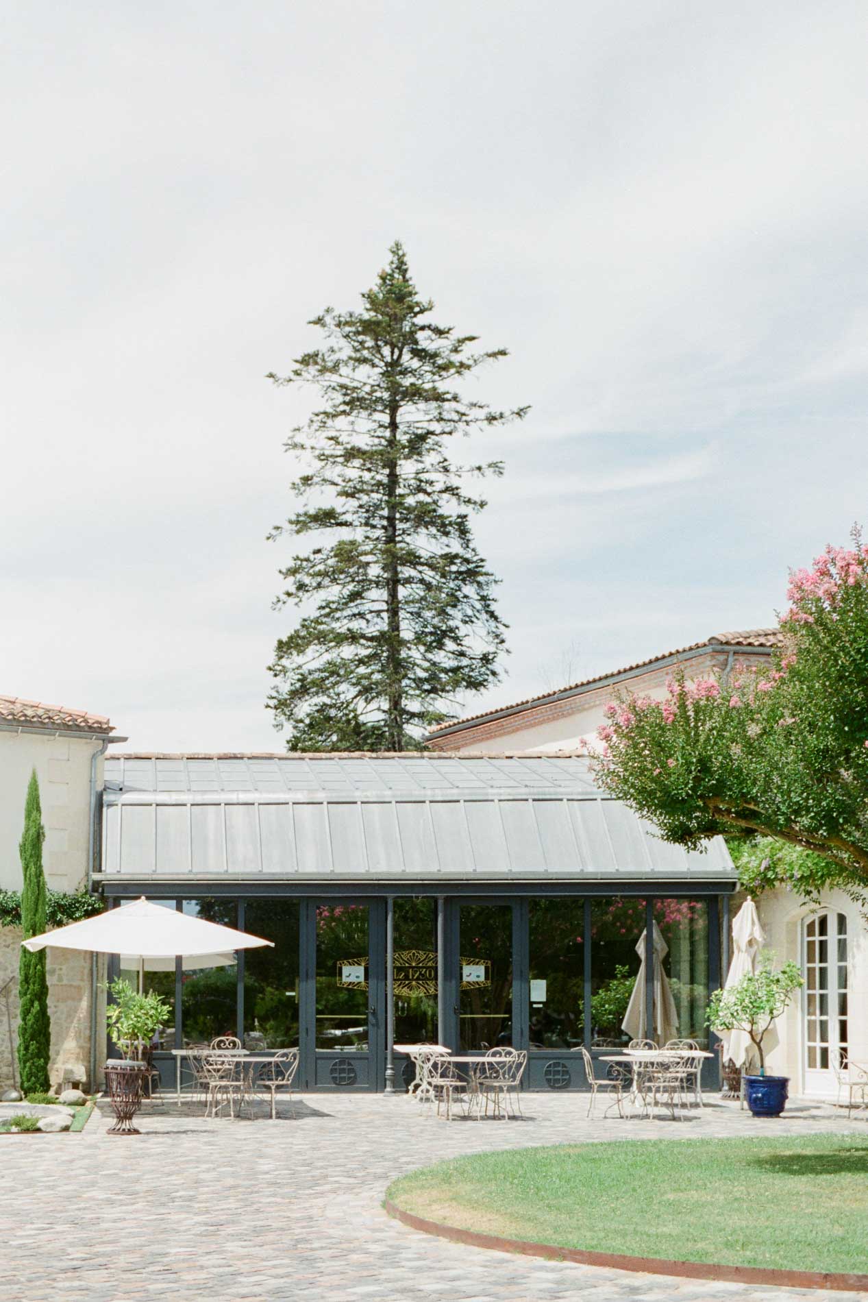 Salle de réception vitrée et pelouse du Domaine de Larchey sous un ciel clair